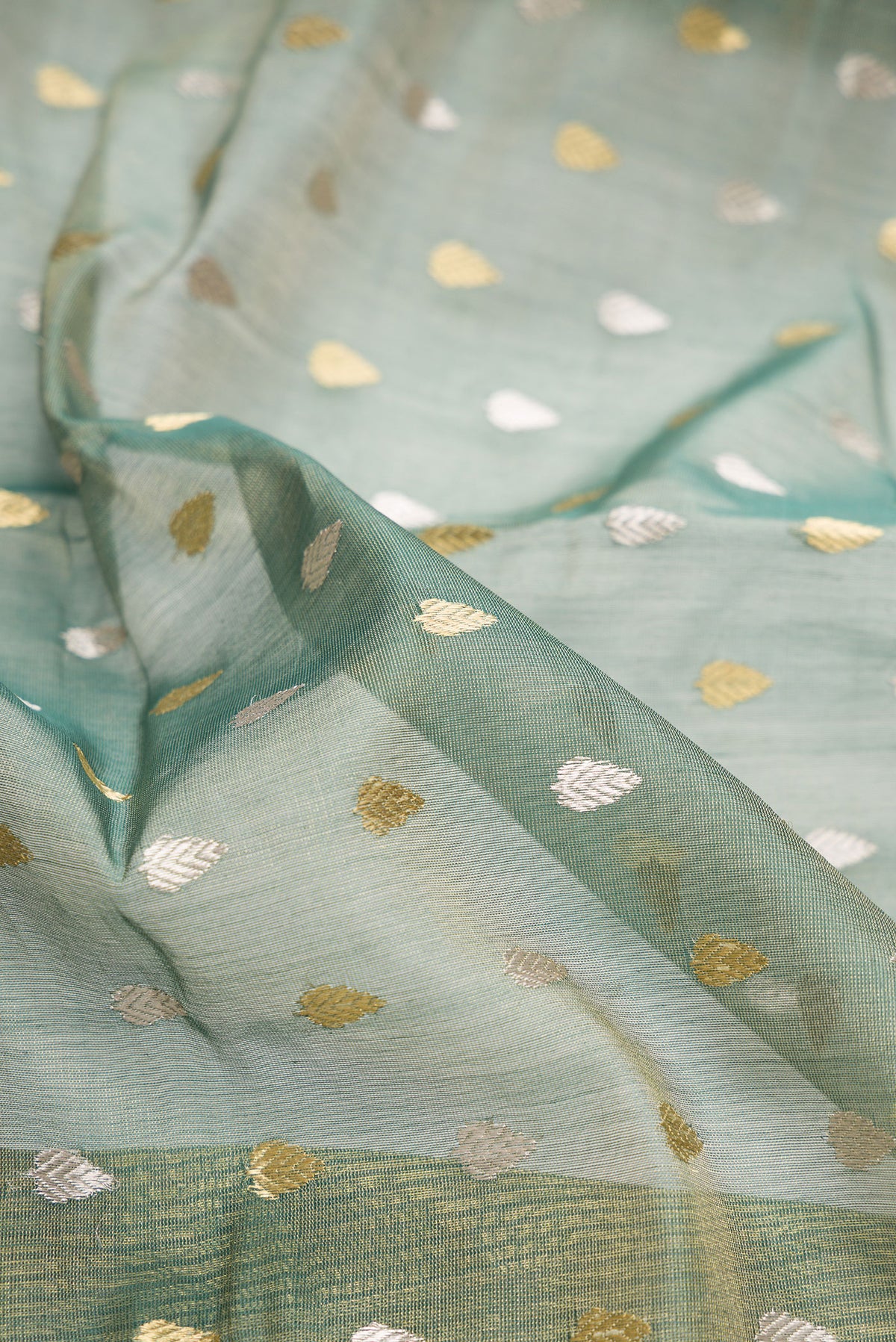 Close up of Green Dual Tone Chanderi Tissue Silk Saree with Zari Butta on the body and Zari Border.  displaying folds
