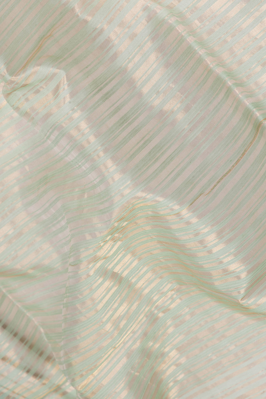 Close up of Pista Green Tussar Silk Saree with Stripes on the body and Thin Zari Line.  displaying folds