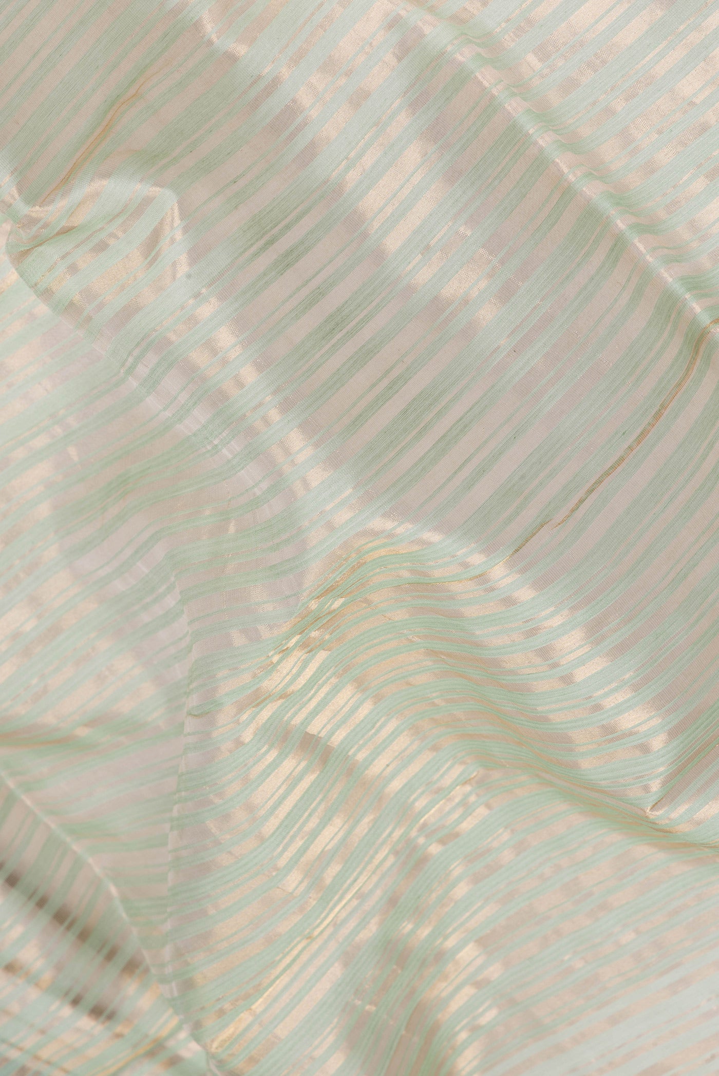 Close up of Pista Green Tussar Silk Saree with Stripes on the body and Thin Zari Line.  displaying folds