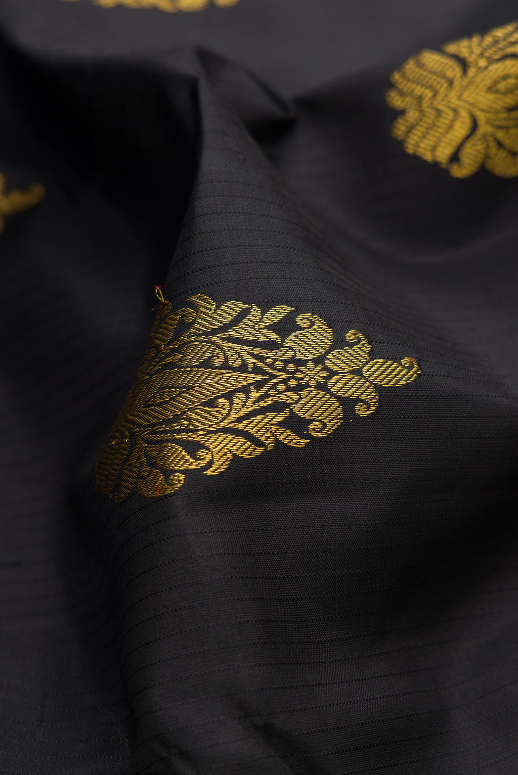 Close up of Black Dual Tone Kanchipuram Silk Saree with Zari Butta on the body and Without Border displaying folds