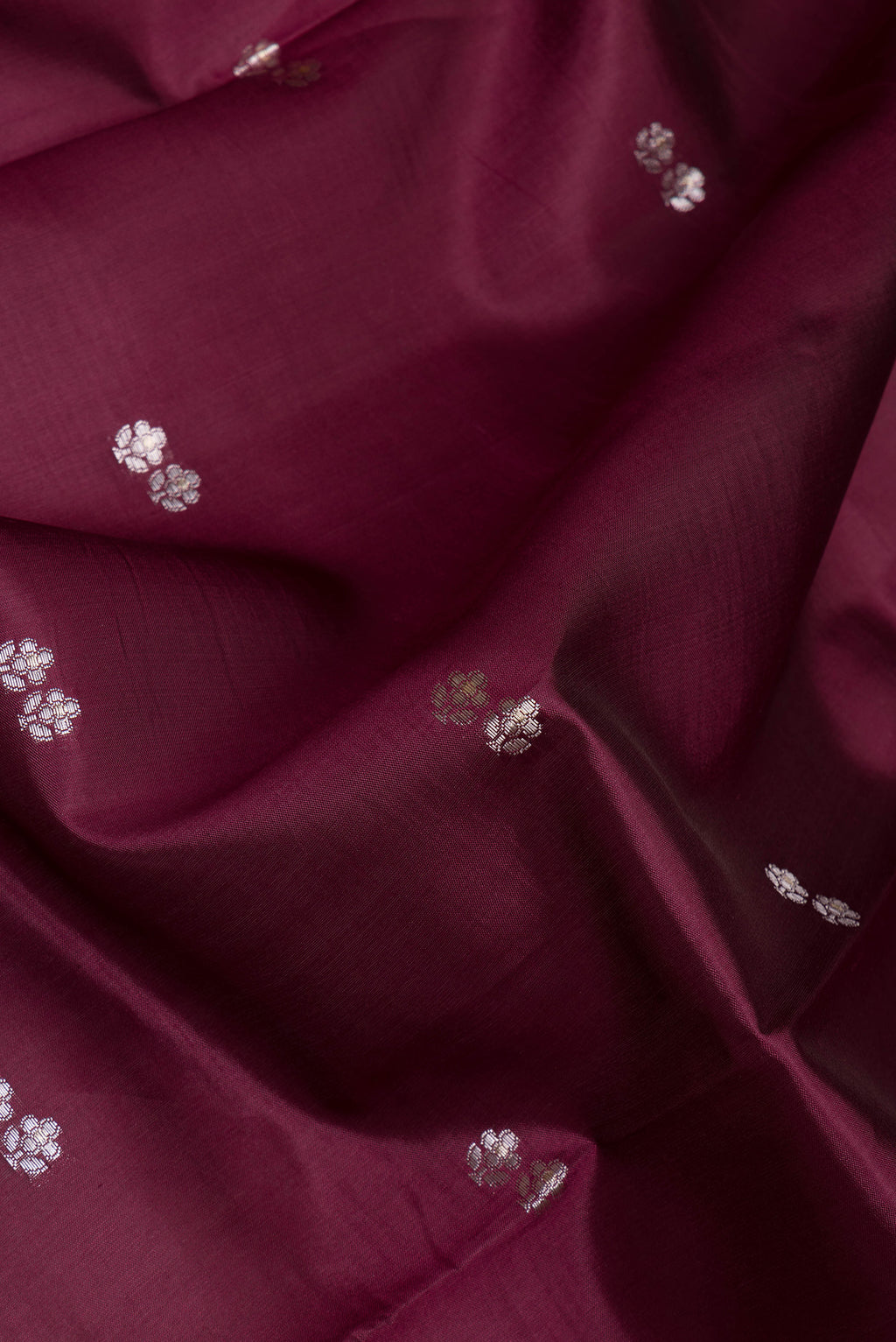 Close up of Maroon Tussar Silk Saree with Zari And Thread Butta on the body and Zari Border.  displaying folds