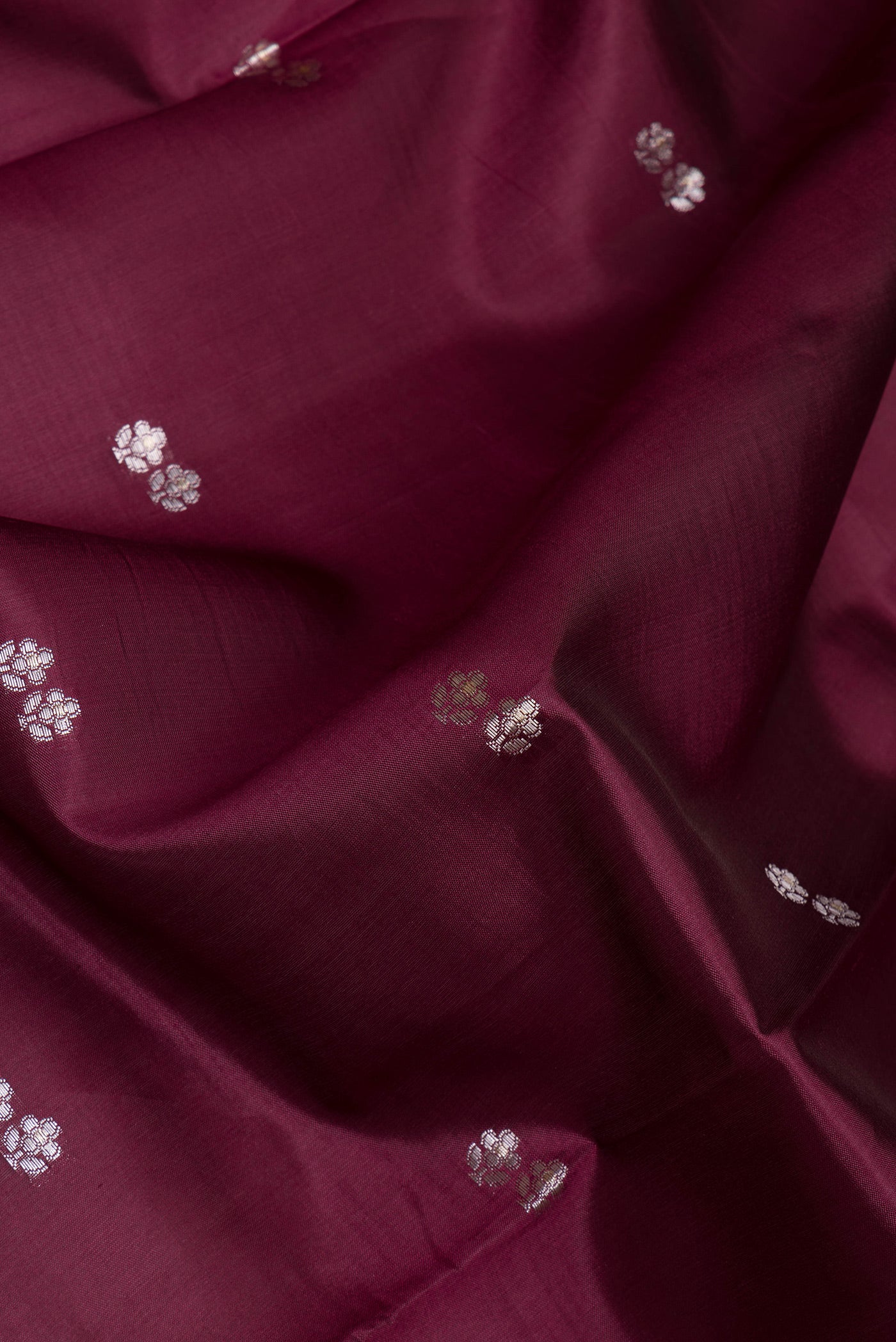 Close up of Maroon Tussar Silk Saree with Zari And Thread Butta on the body and Zari Border.  displaying folds