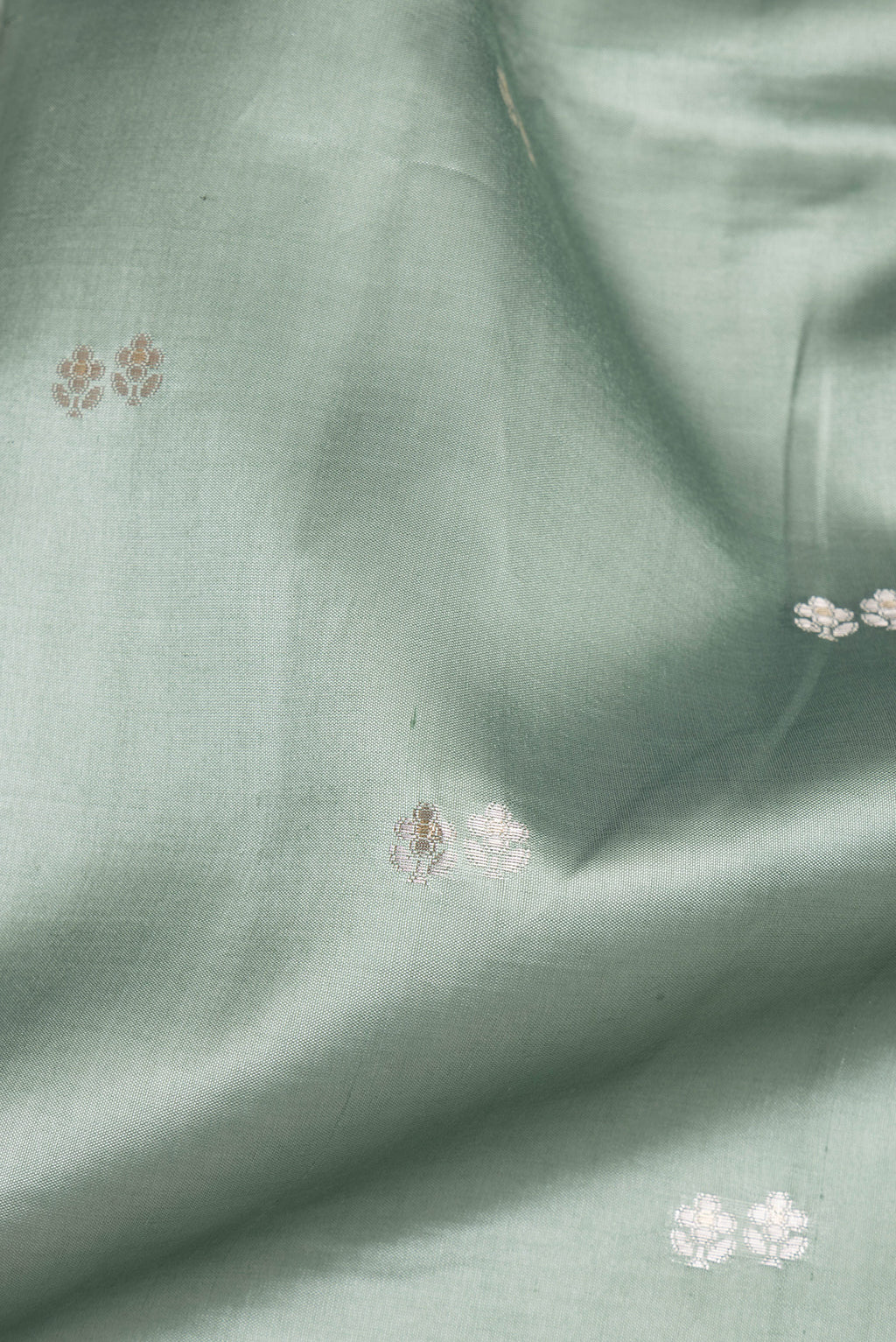 Close up of Pure Silk Light Green Dual Tone Tussar Saree with Zari Butta on the body and Fancy Border.  displaying folds