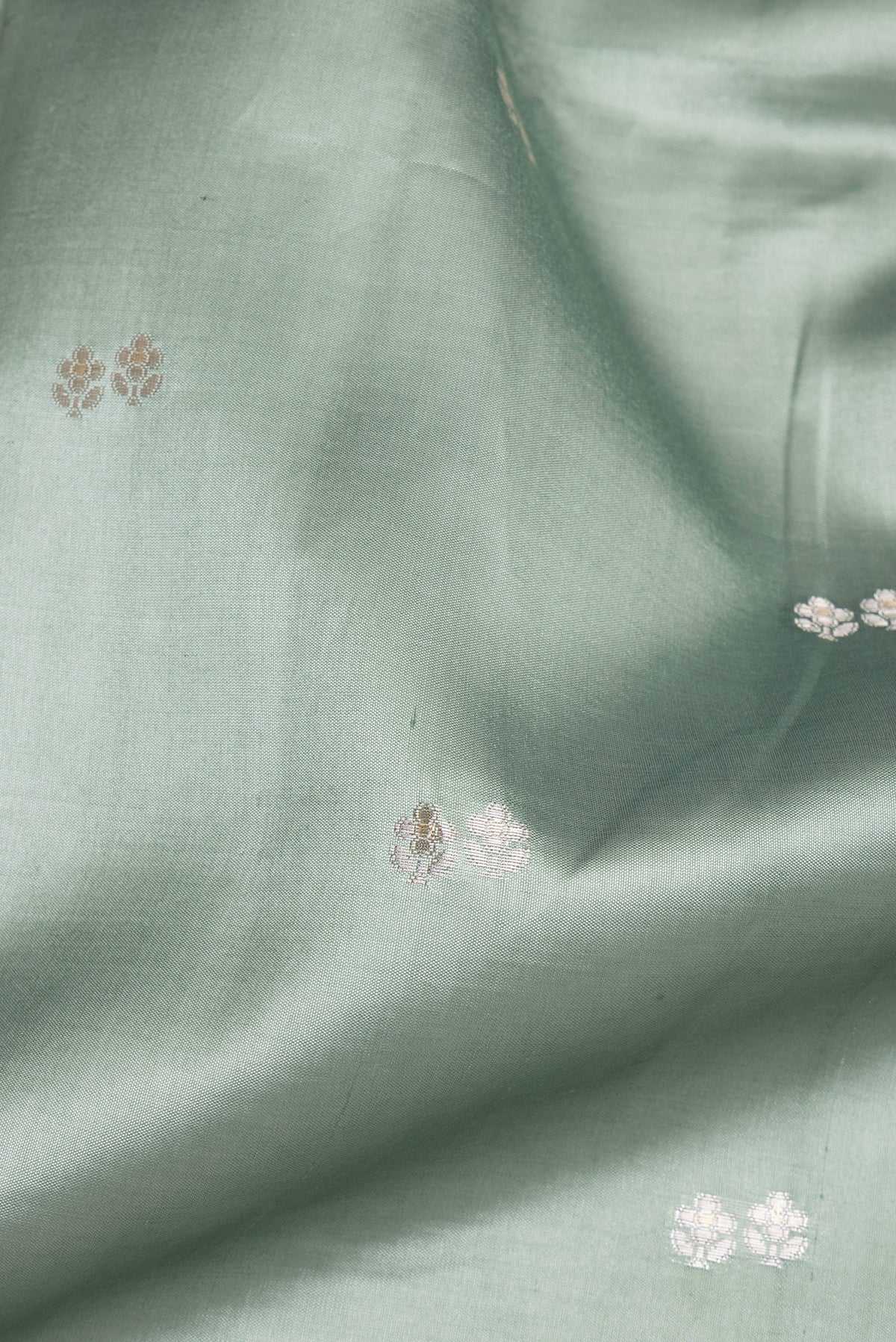 Close up of Pure Silk Light Green Dual Tone Tussar Saree with Zari Butta on the body and Fancy Border.  displaying folds