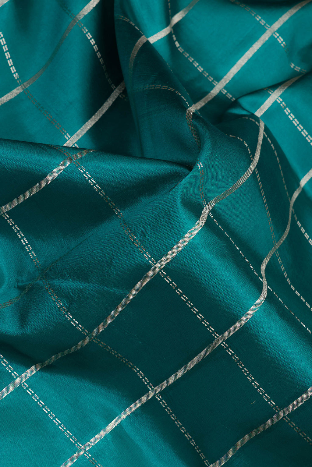 Close up of Peacock Blue Tussar Silk Saree with Checked design on the body and Zari Border.  displaying folds