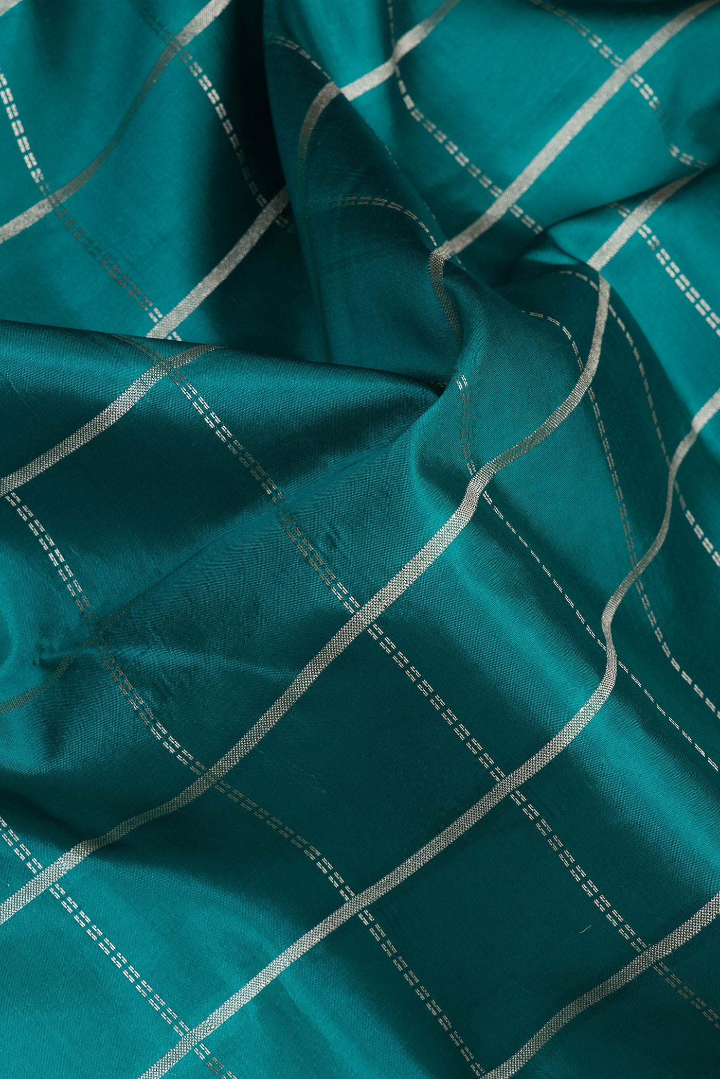 Close up of Peacock Blue Tussar Silk Saree with Checked design on the body and Zari Border.  displaying folds