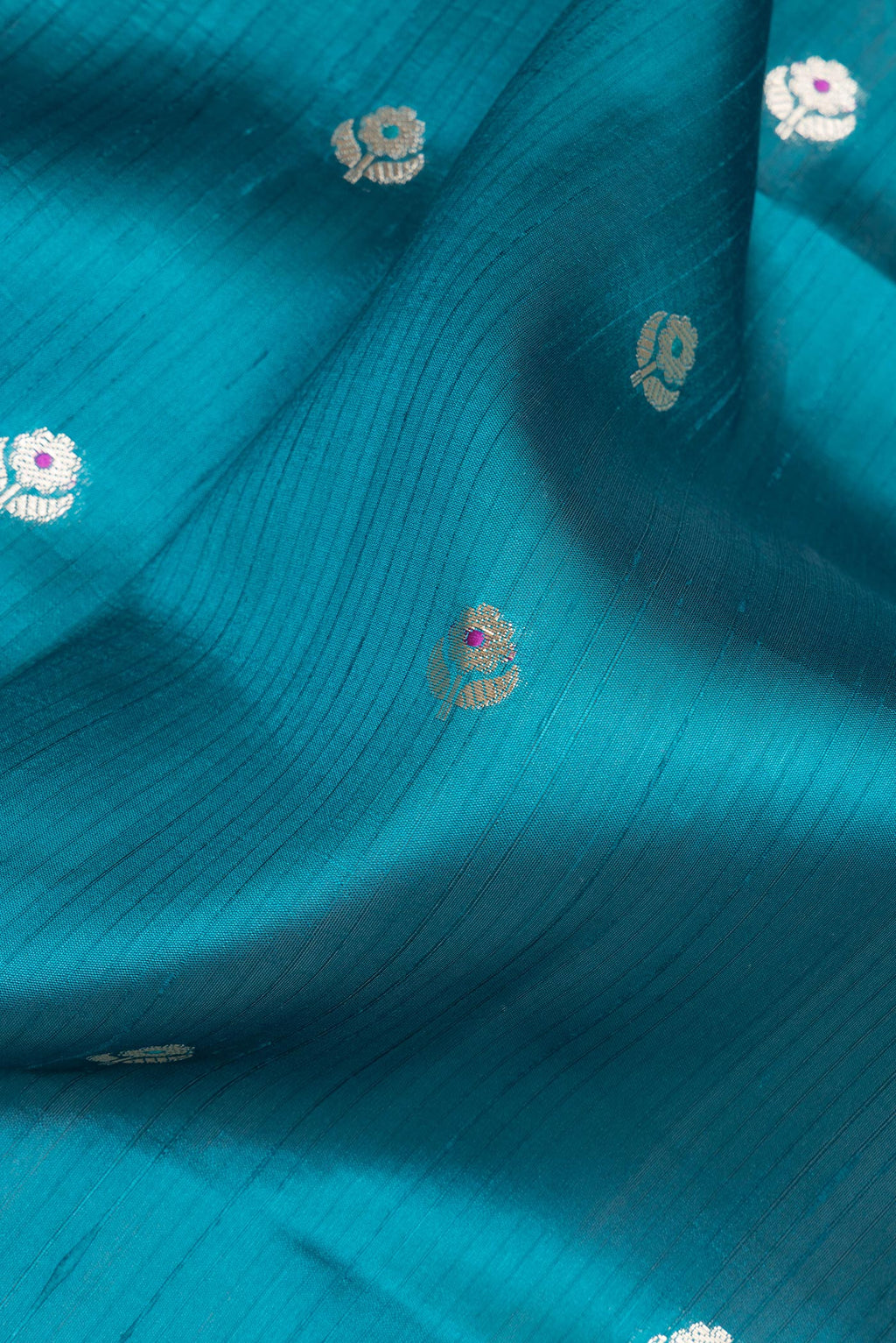 Close up of Pure Silk Peacock Blue Dual Tone Tussar Saree with Zari Butta on the body and Fancy Border.  displaying folds