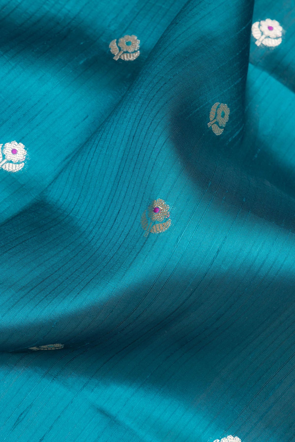 Close up of Pure Silk Peacock Blue Dual Tone Tussar Saree with Zari Butta on the body and Fancy Border.  displaying folds