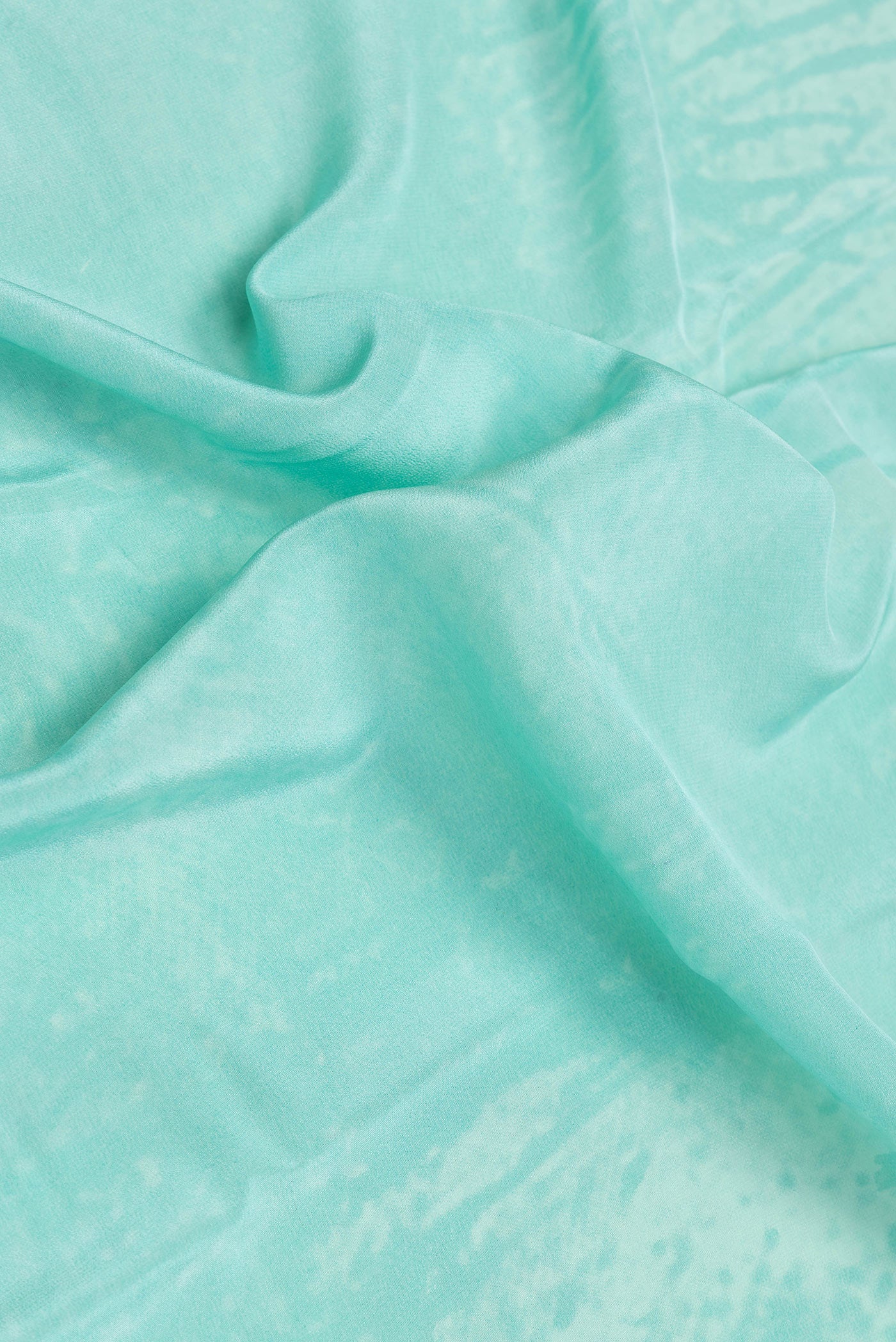 Close up of Sky Blue Dual Tone Mysore Crepe Saree with Printed design on the body and Plain Border.  displaying folds