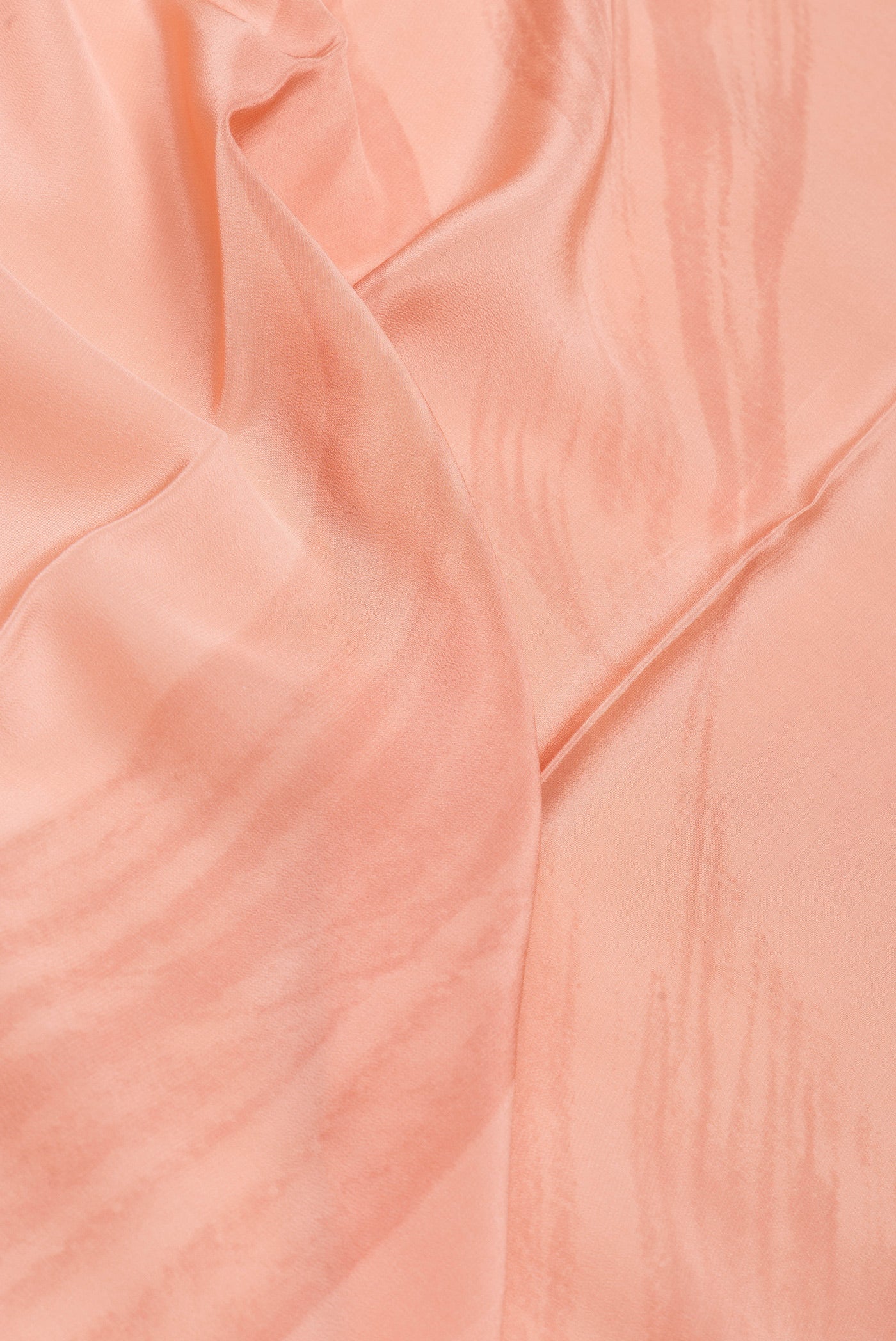 Close up of Peach Crepe Saree with Printed design on the body and Plain Border.  displaying folds