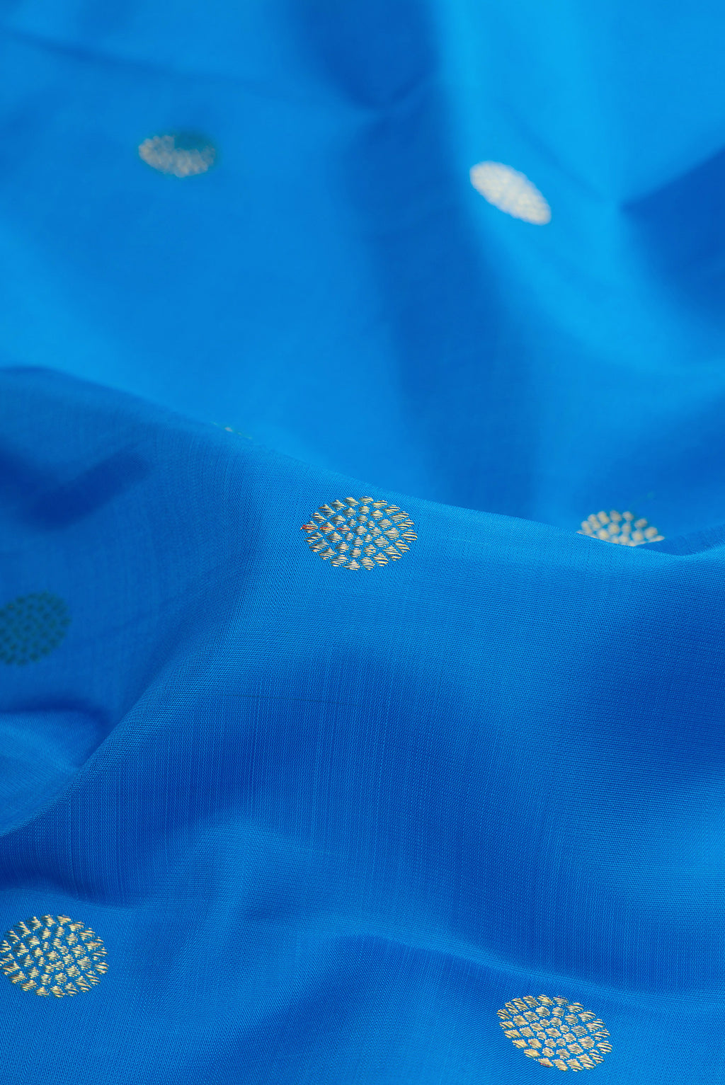 Close up of Pure Silk Sky Blue Kanjivaram Saree with Zari Butta on the body and Zari Border.  displaying folds