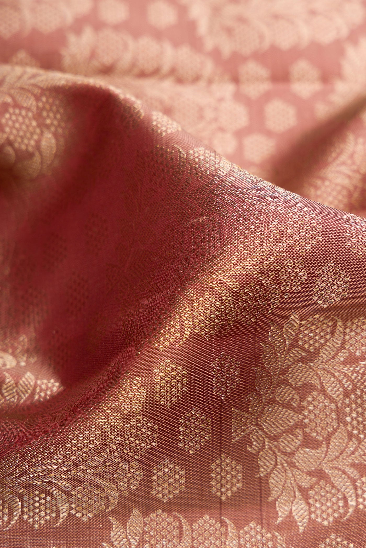 Close up of Rose Gold Dual Tone Kanchipuram Silk Saree with Zari Brocade on the body and Zari Border.  displaying folds
