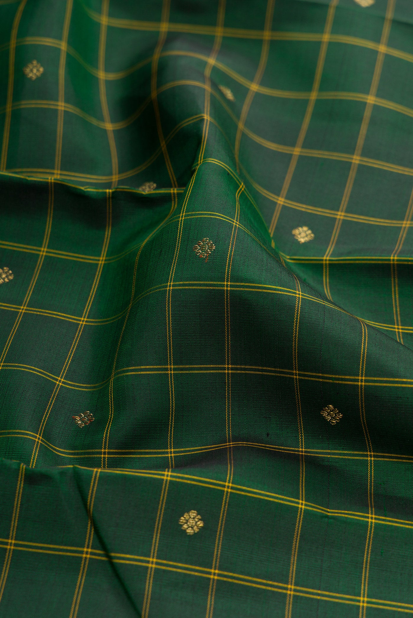 Close up of Bottle Green Kanchipuram Silk Saree with Checked design on the body and Thin Zari Line.  displaying folds