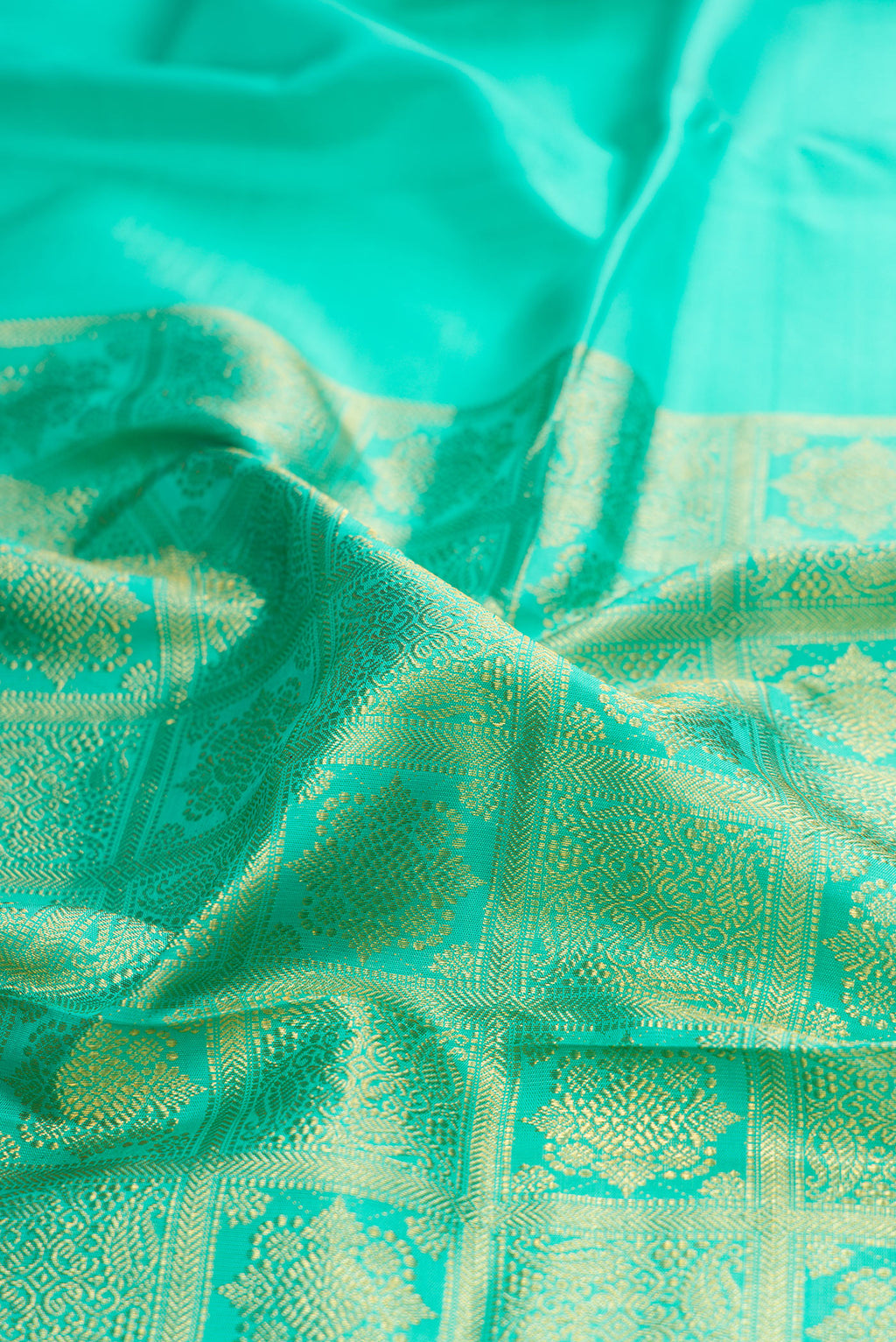 Close up of Pure Silk Turquoise Kanjivaram Saree with Zari Butta on the body and Without Border.  displaying folds