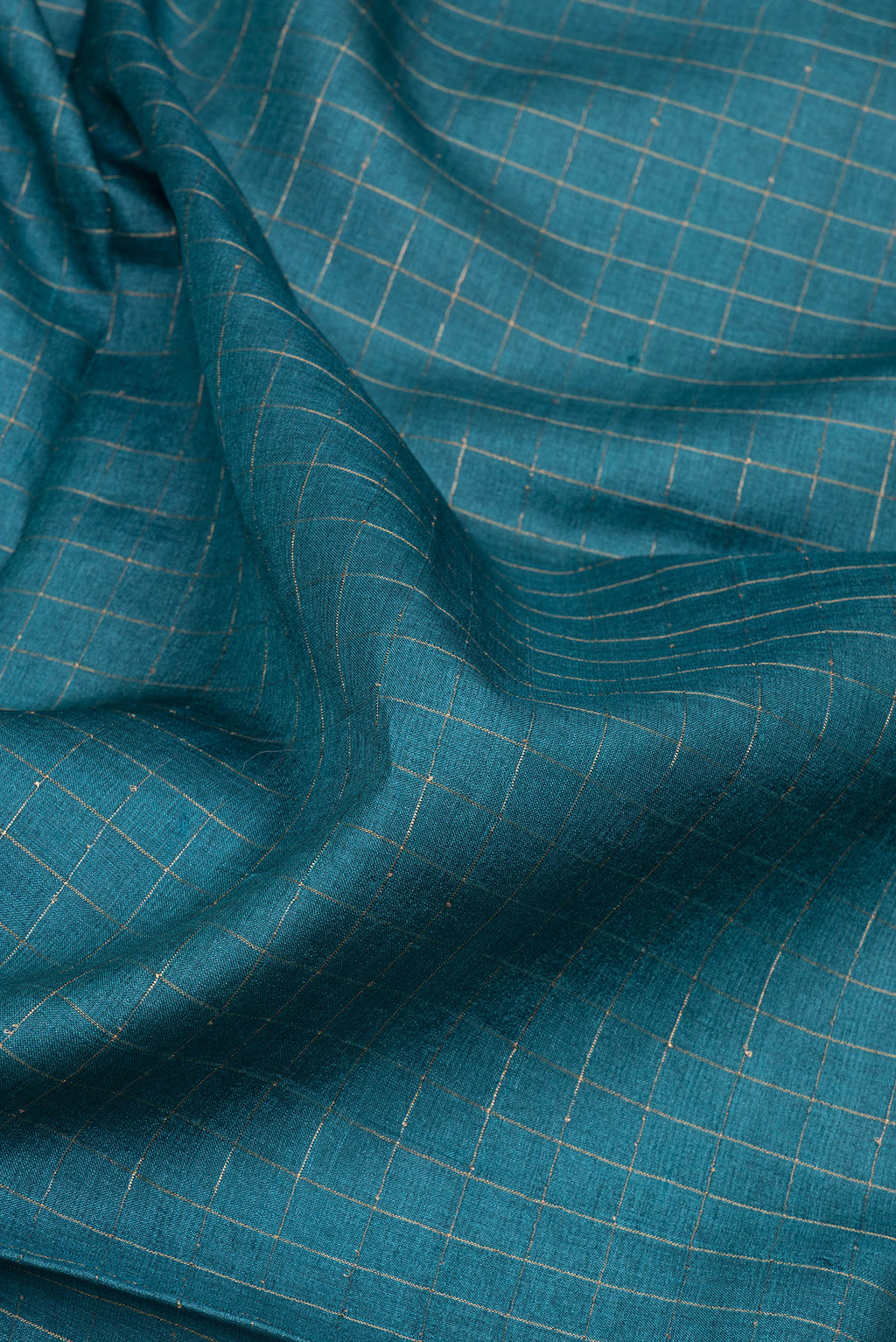 Close up of Peacock Blue Tussar Silk Saree with Checked design on the body and Printed Border.  displaying folds