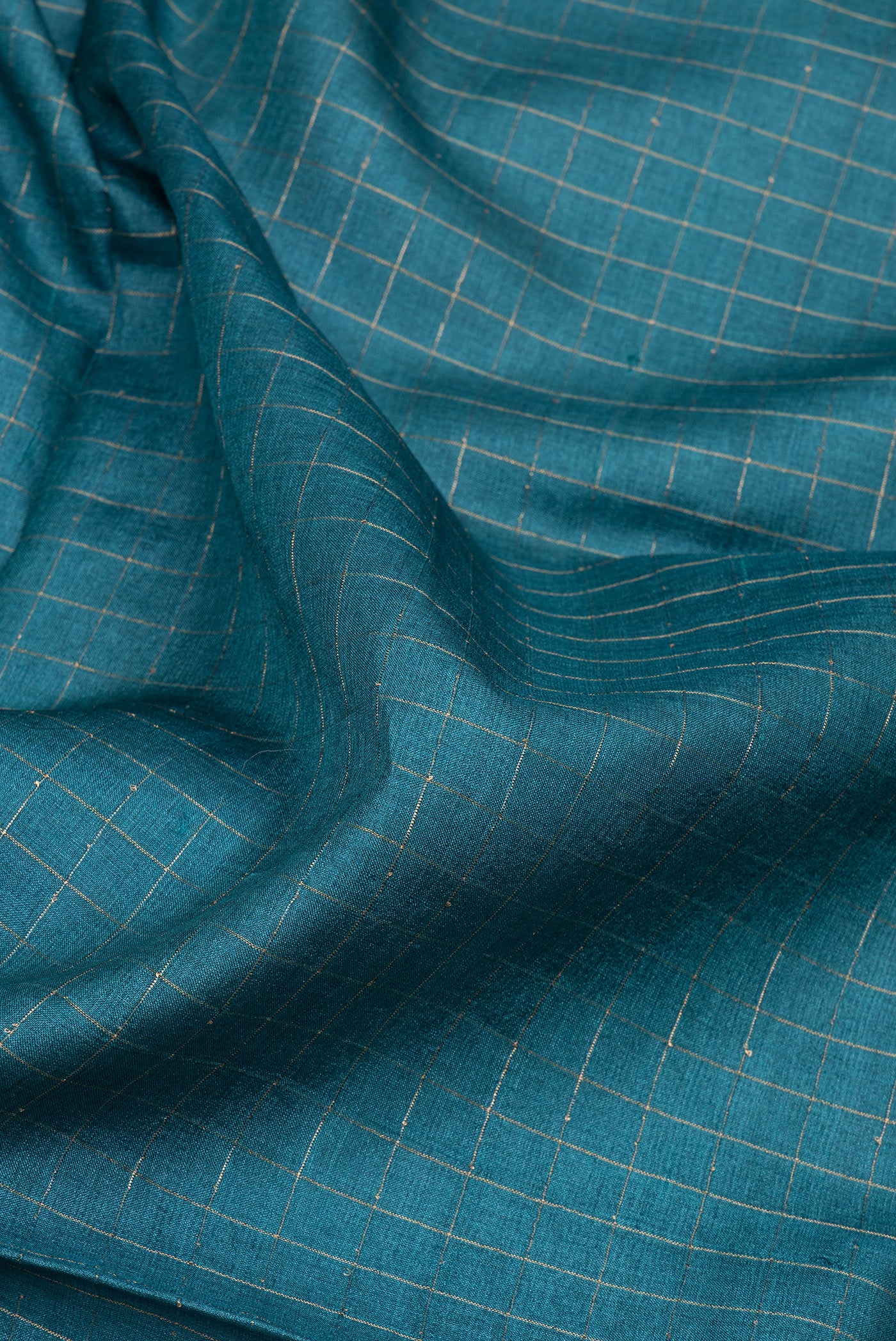 Close up of Peacock Blue Tussar Silk Saree with Checked design on the body and Printed Border.  displaying folds