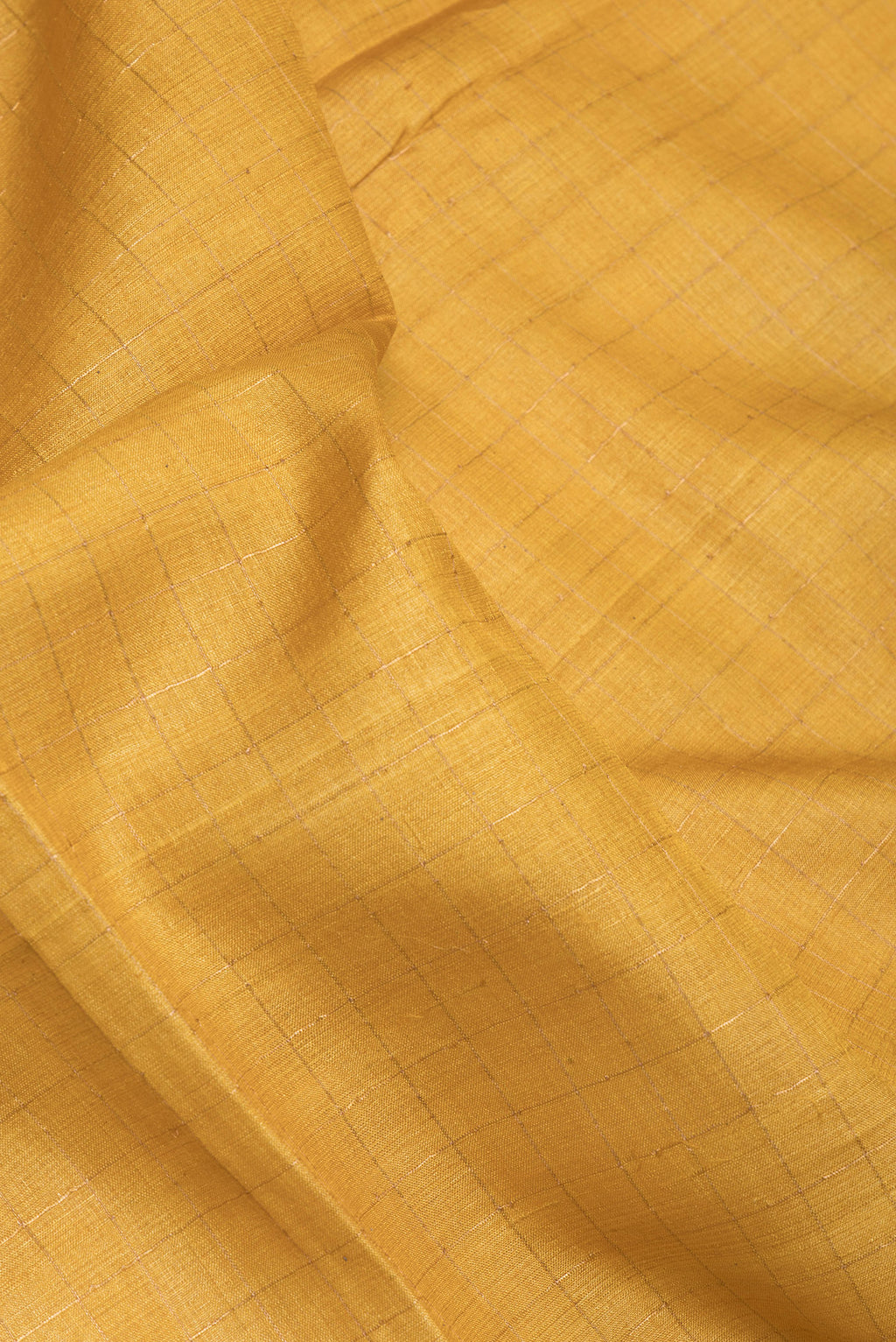 Close up of Mustard Tussar Silk Saree with Checked design on the body and Printed Border.  displaying folds