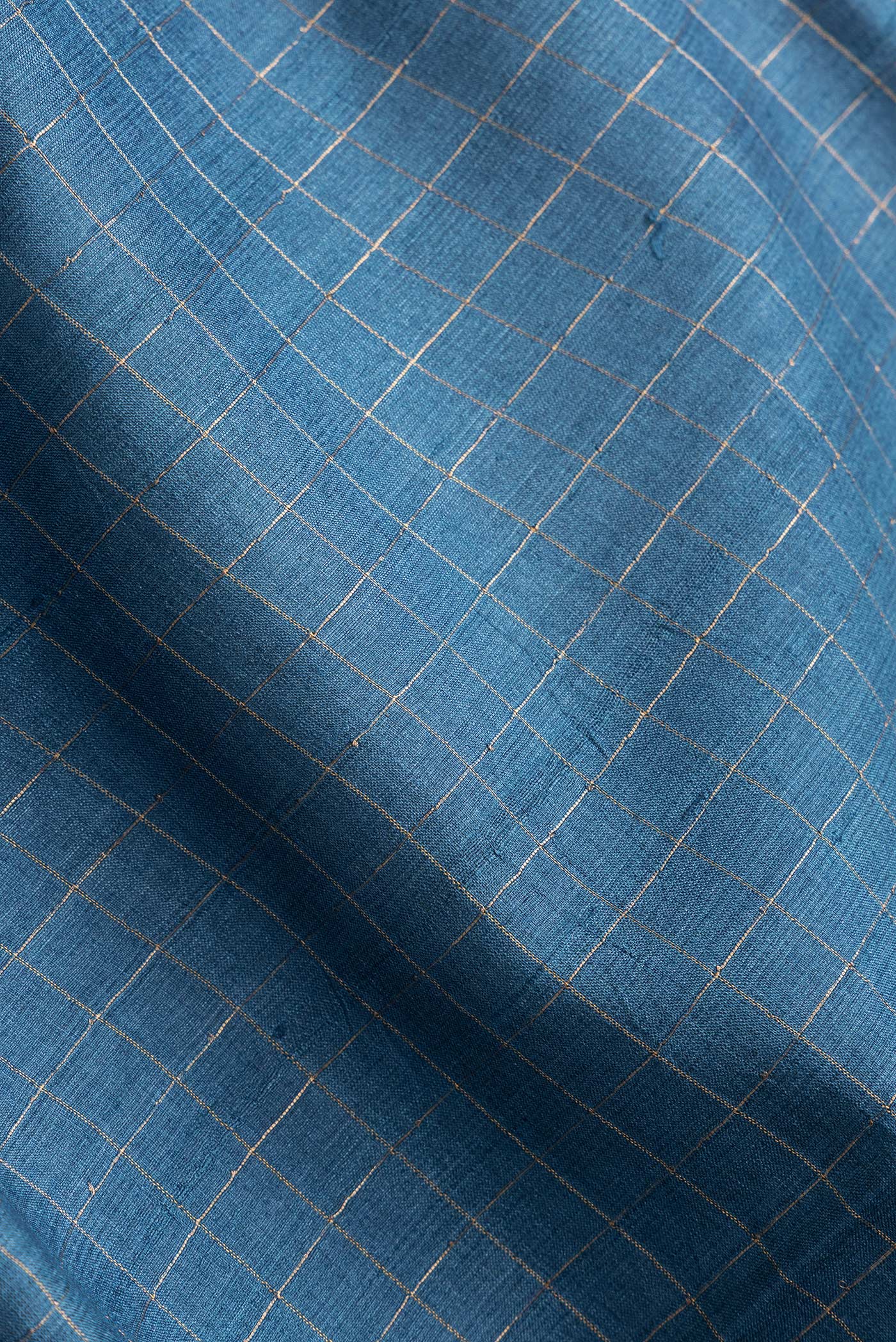 Close up of Peacock Blue Dual Tone Tussar Silk Saree with Checked design on the body and Printed Border.  displaying folds