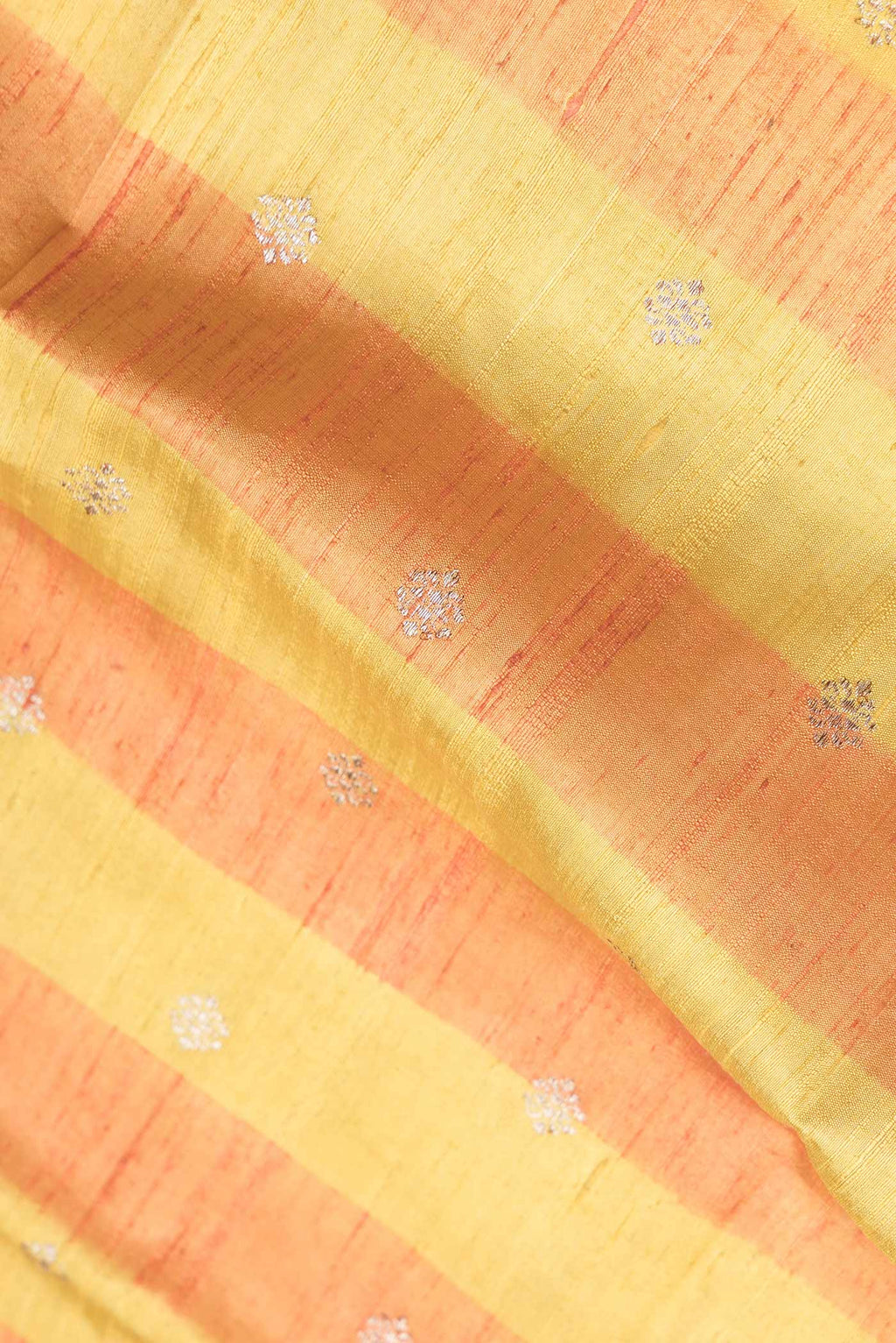 Close up of Yellow Dual Tone Tussar Saree with Zari Butta on the body and Zari Border.  displaying folds