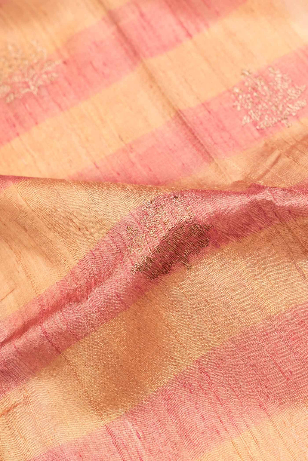 Close up of Beige Dual Tone Tussar Saree with Zari Butta on the body and Zari Border.  displaying folds