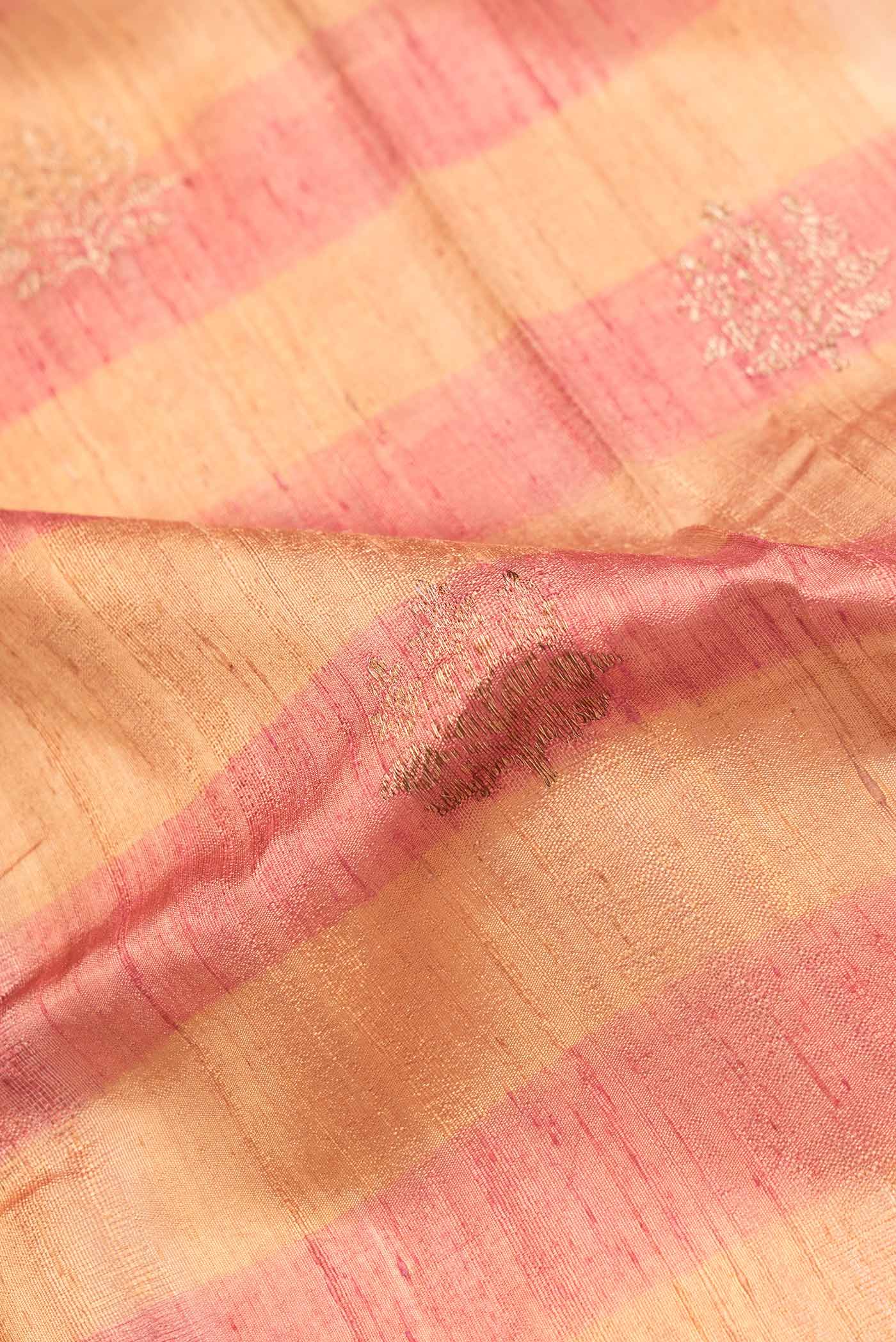 Close up of Beige Dual Tone Tussar Saree with Zari Butta on the body and Zari Border.  displaying folds