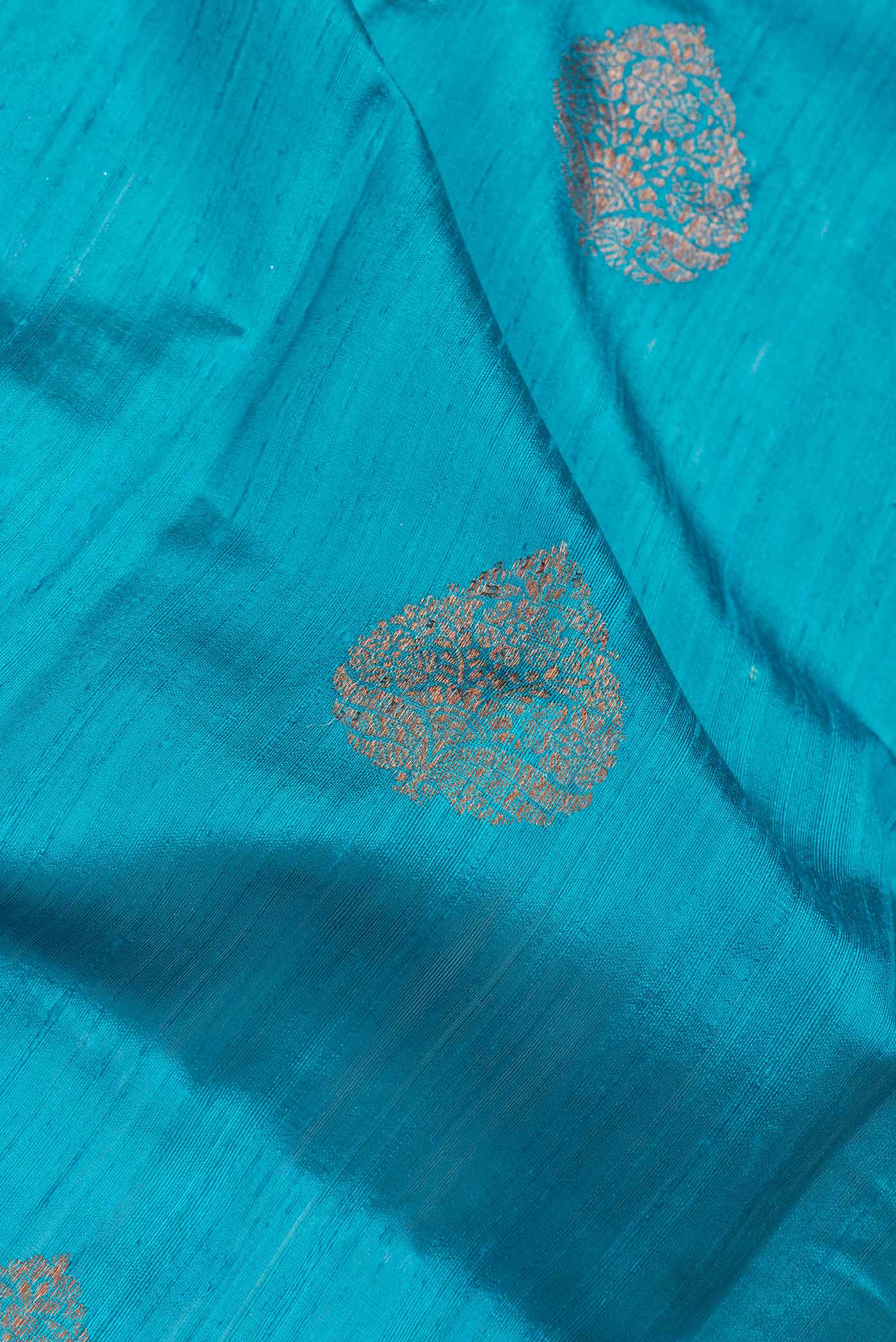 Close up of Peacock Blue Dual Tone Tussar Saree with Zari Butta on the body and Zari Border.  displaying folds