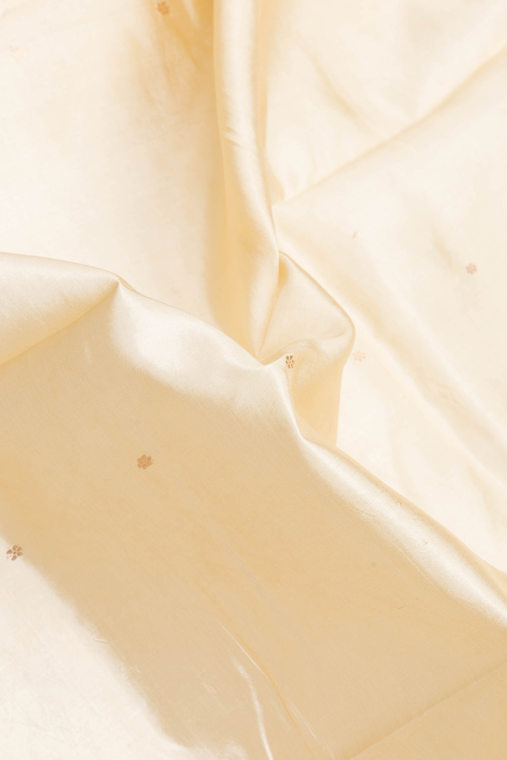 Close up of Beige Dual Tone Banarasi Katan Silk Saree with Zari Butta on the body and Fancy Border.  displaying folds