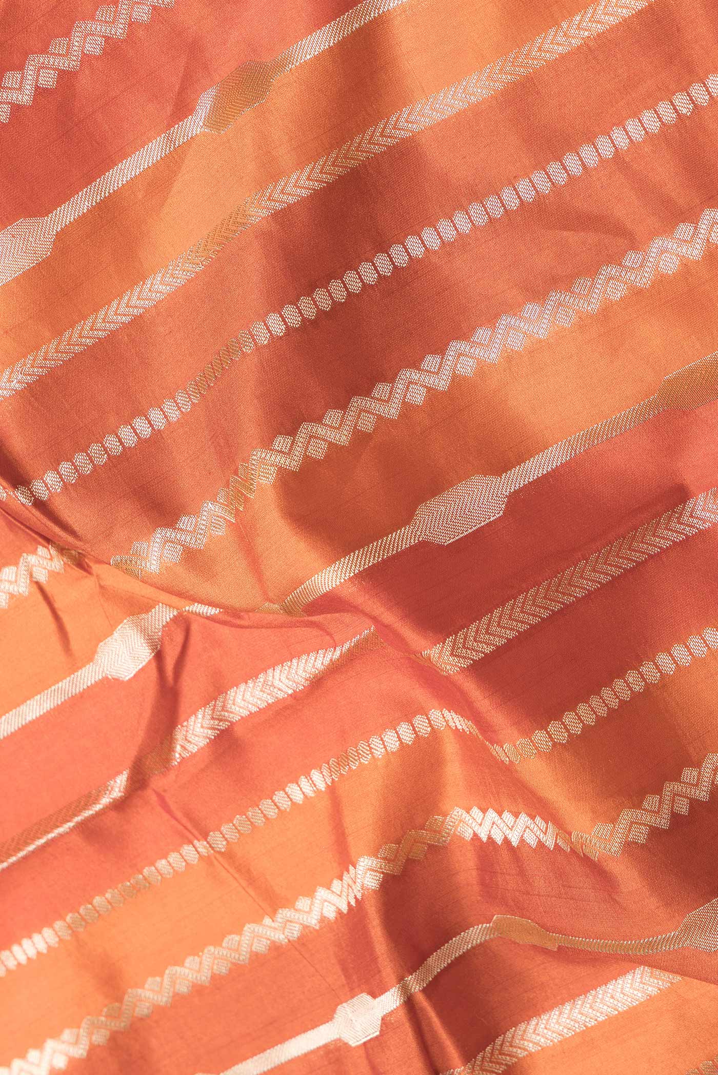 Close up of Orange Dual Tone Tussar Silk Saree with Stripes on the body and Zari Border.  displaying folds