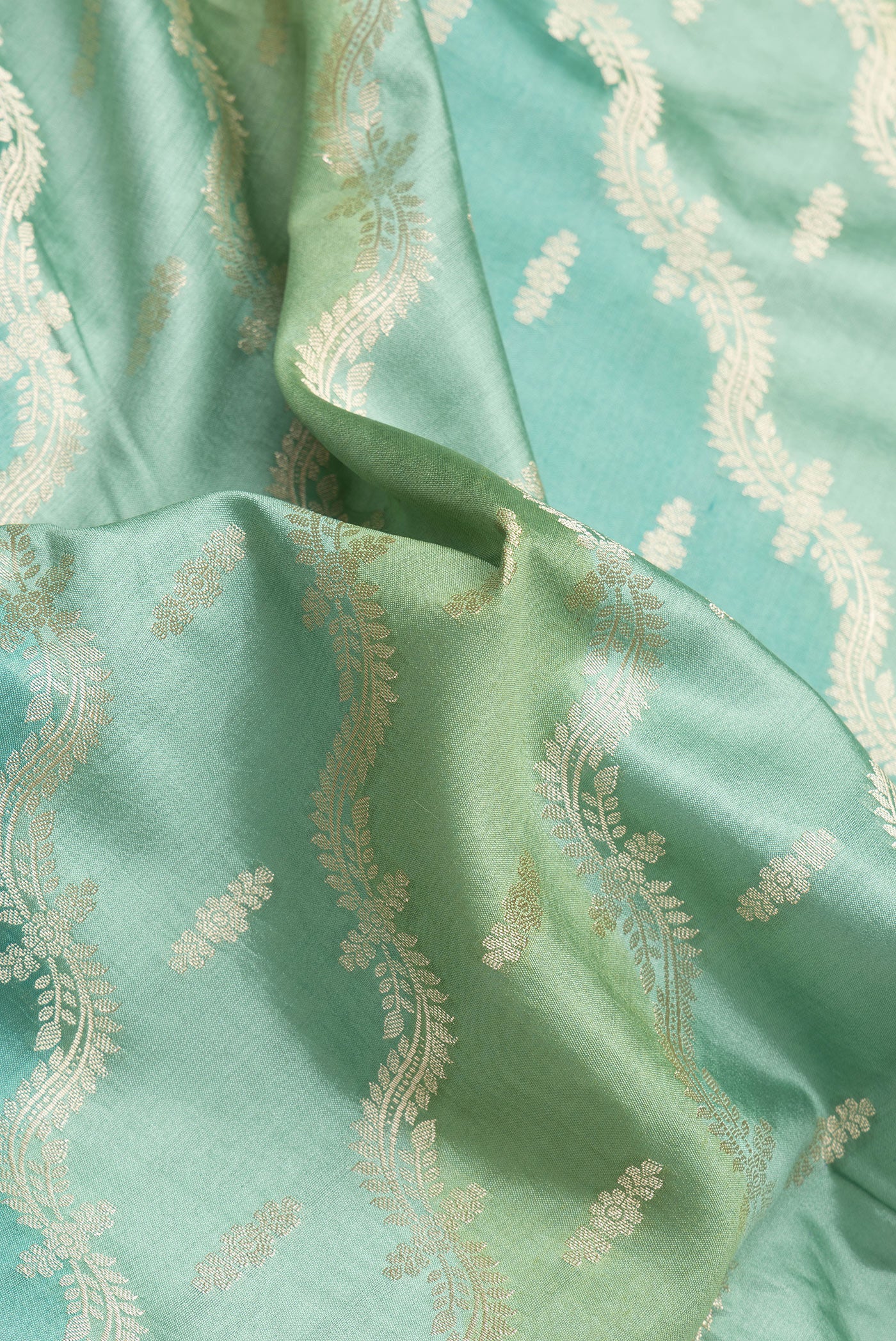 Close up of Green Dual Tone Banarasi Raw Silk Saree with Zari Brocade on the body and Zari Border.  displaying folds