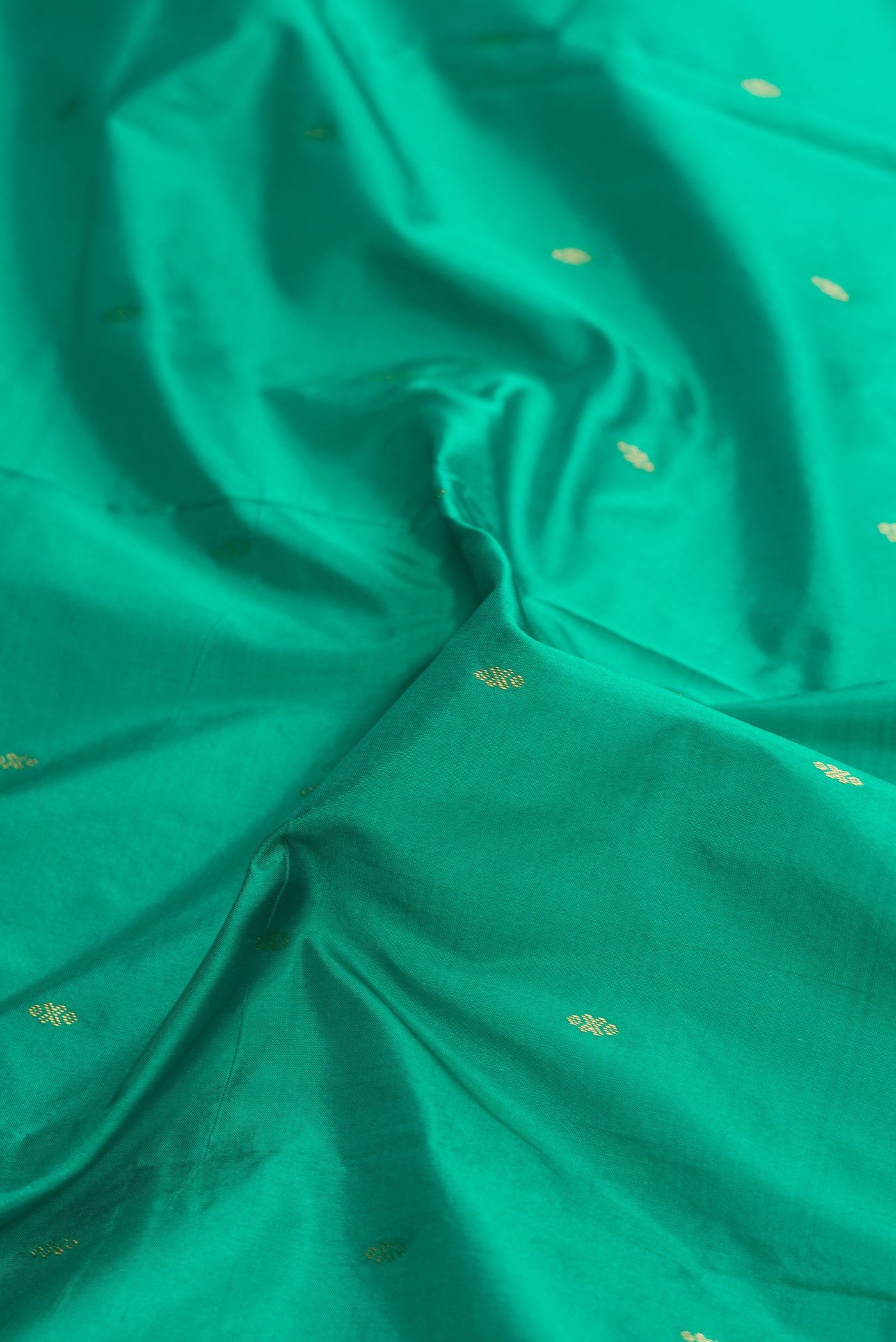 Close up of Green Dual Tone Kanchipuram Silk Saree with Zari Butta on the body and Zari Border.  displaying folds