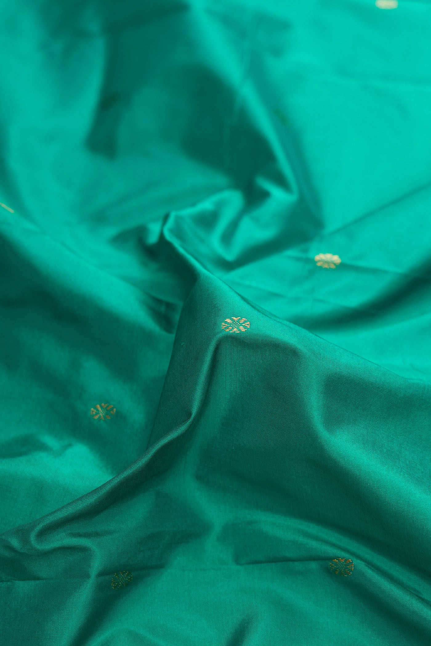 Close up of Green Dual Tone Kanchipuram Silk Saree with Zari Butta on the body and Zari Border.  displaying folds