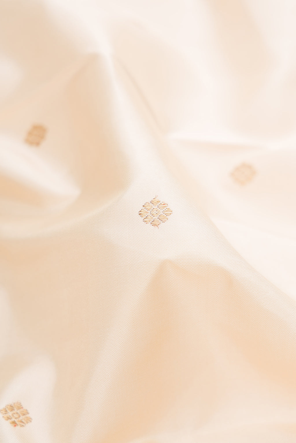 Close up of Pure Silk Pure Zari Cream Kanchipuram Saree with Zari Butta on the body and Temple Border.  displaying folds