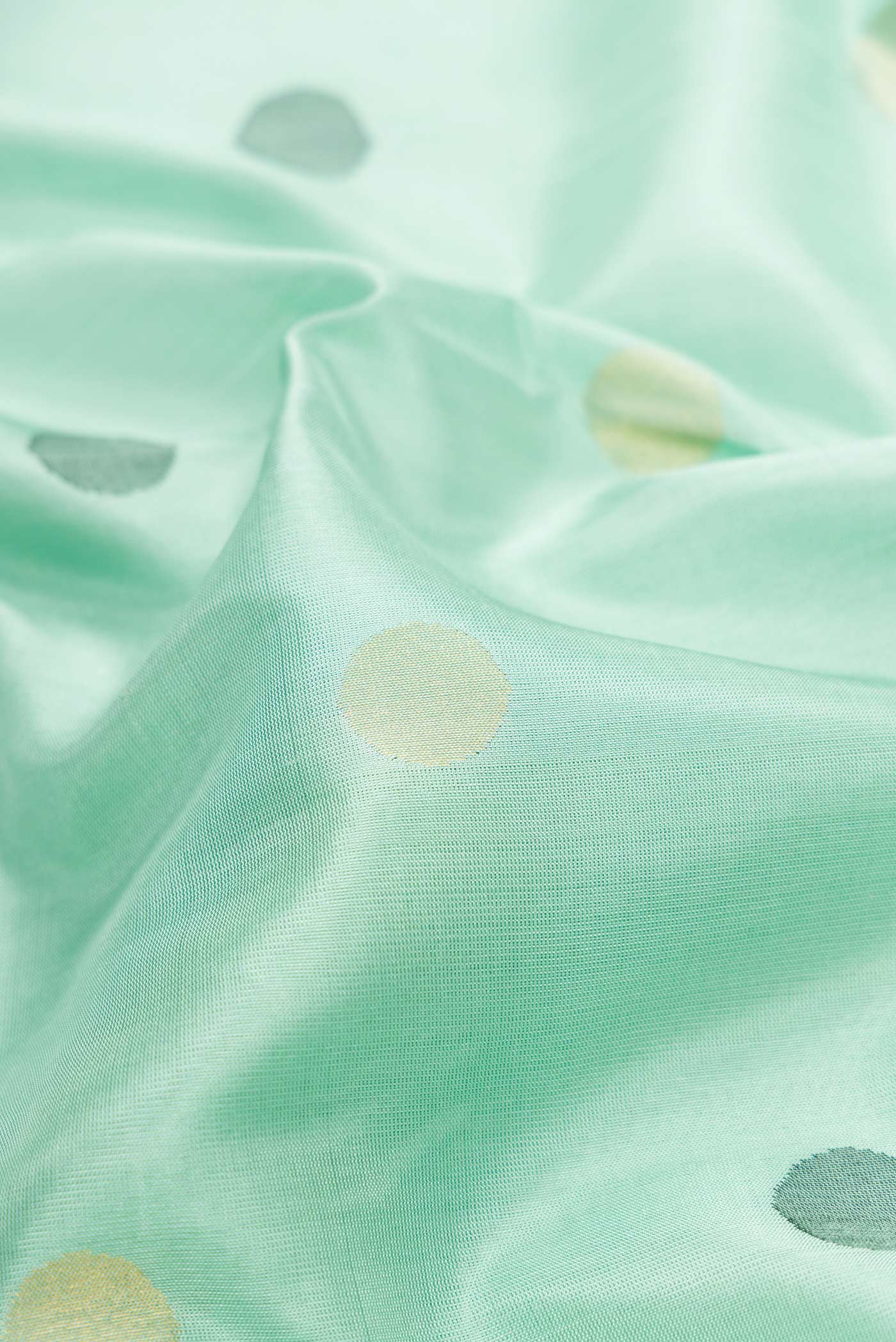 Close up of Light Green Dual Tone Uppada Silk Saree with Zari And Thread Butta on the body and Fancy Border.  displaying folds