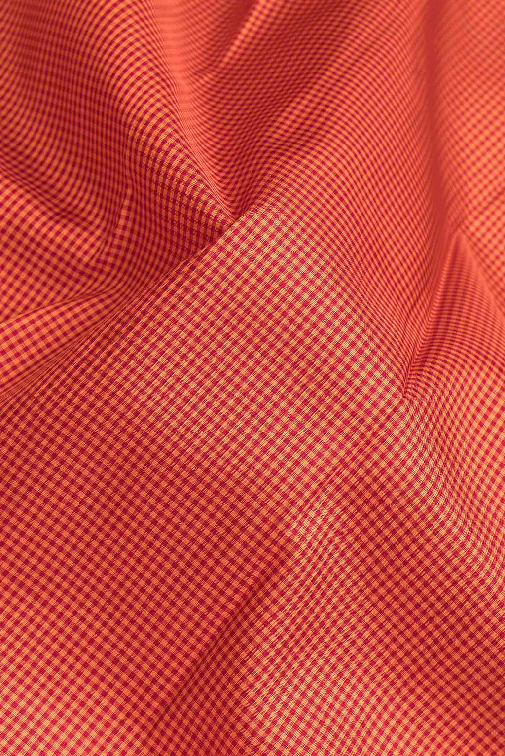 Close up of Orange Dual Tone Kanchipuram Silk Saree with Checked design on the body and Zari Border.  displaying folds