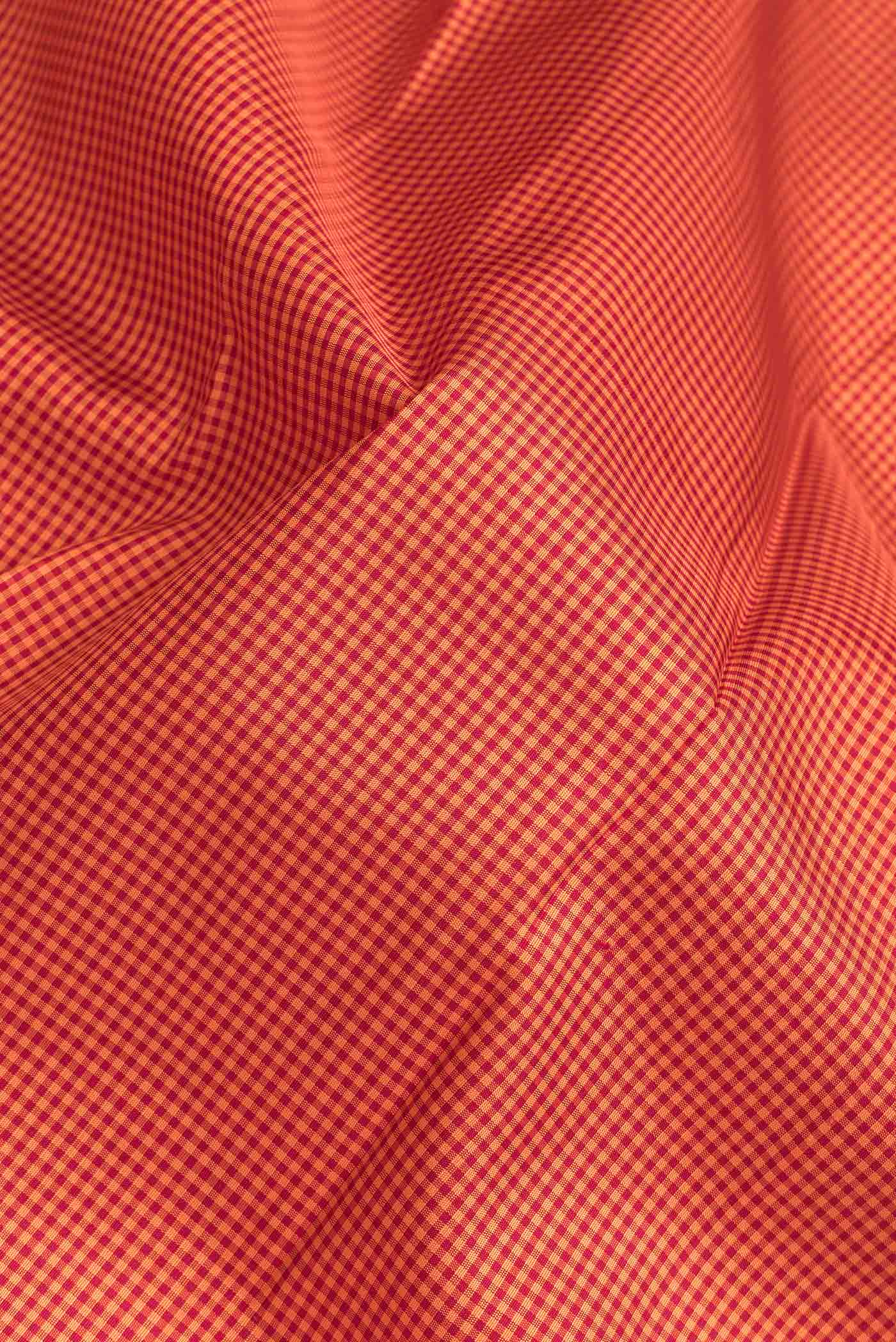 Close up of Orange Dual Tone Kanchipuram Silk Saree with Checked design on the body and Zari Border.  displaying folds