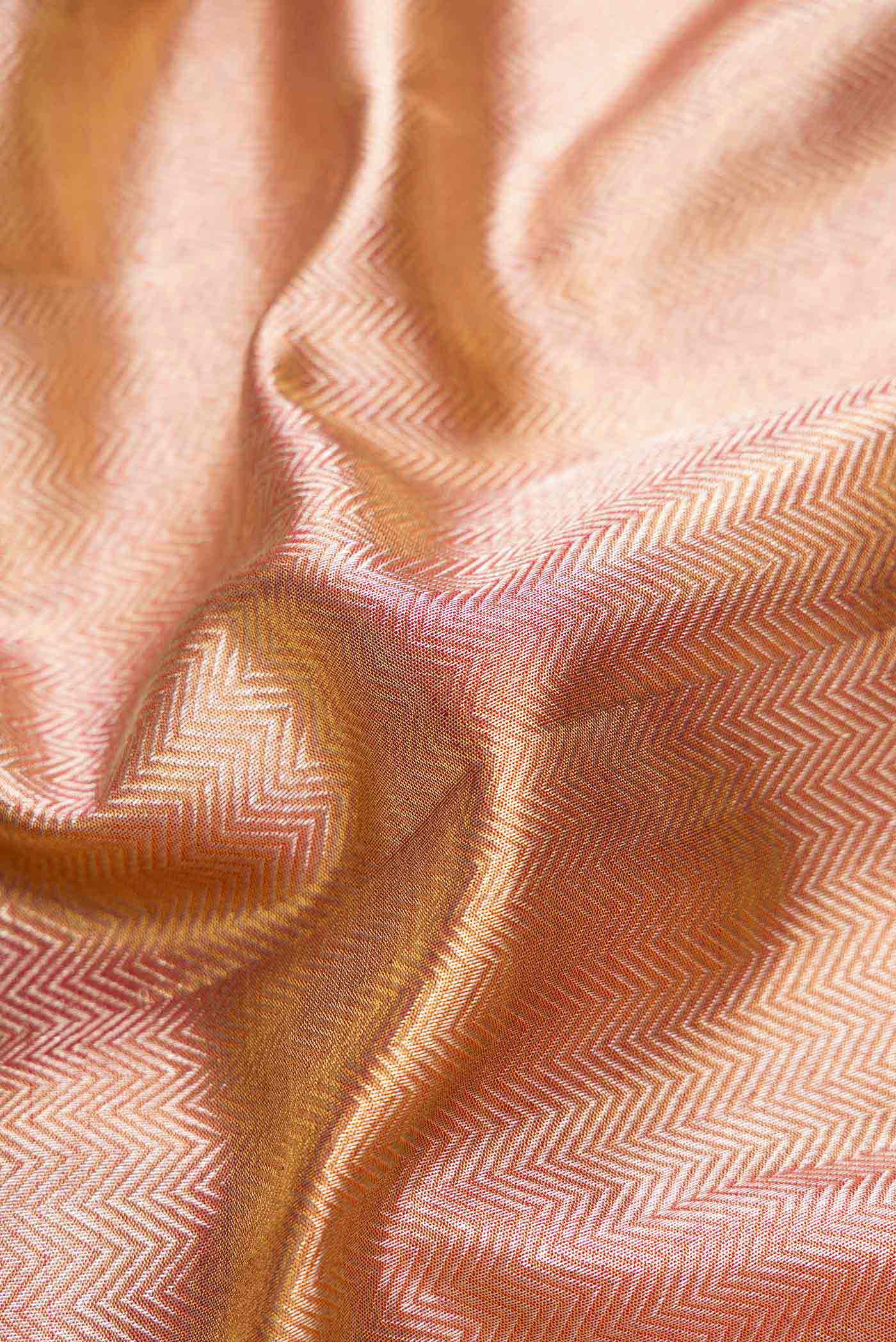Close up of Rose Gold Dual Tone Kanjivaram Tissue Silk Saree with Zari Brocade on the body and Zari Border.  displaying folds