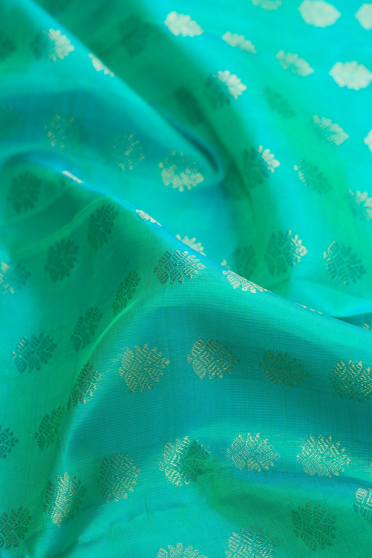 Close up of Pure Silk Pure Zari Sea Green Dual Tone Kanjivaram Saree with Zari Butta on the body and Zari Border.  displaying folds