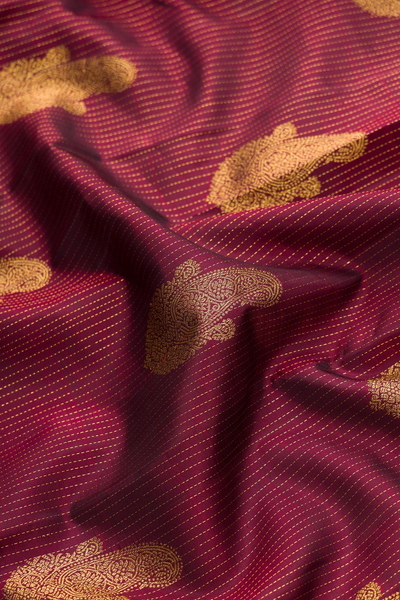 Close up of Pure Silk Pure Zari Maroon Dual Tone Kanjivaram Saree with Stripes on the body and Zari Border.  displaying folds