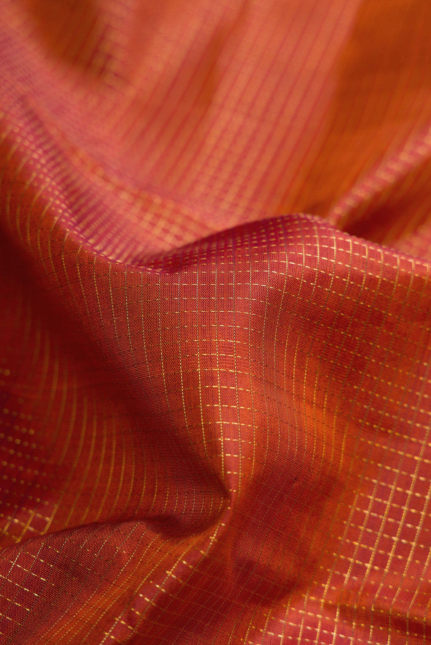 Close up of Brick Orange Dual Tone Kanjivaram Silk Saree with Checked design on the body and Fancy Border.  displaying folds