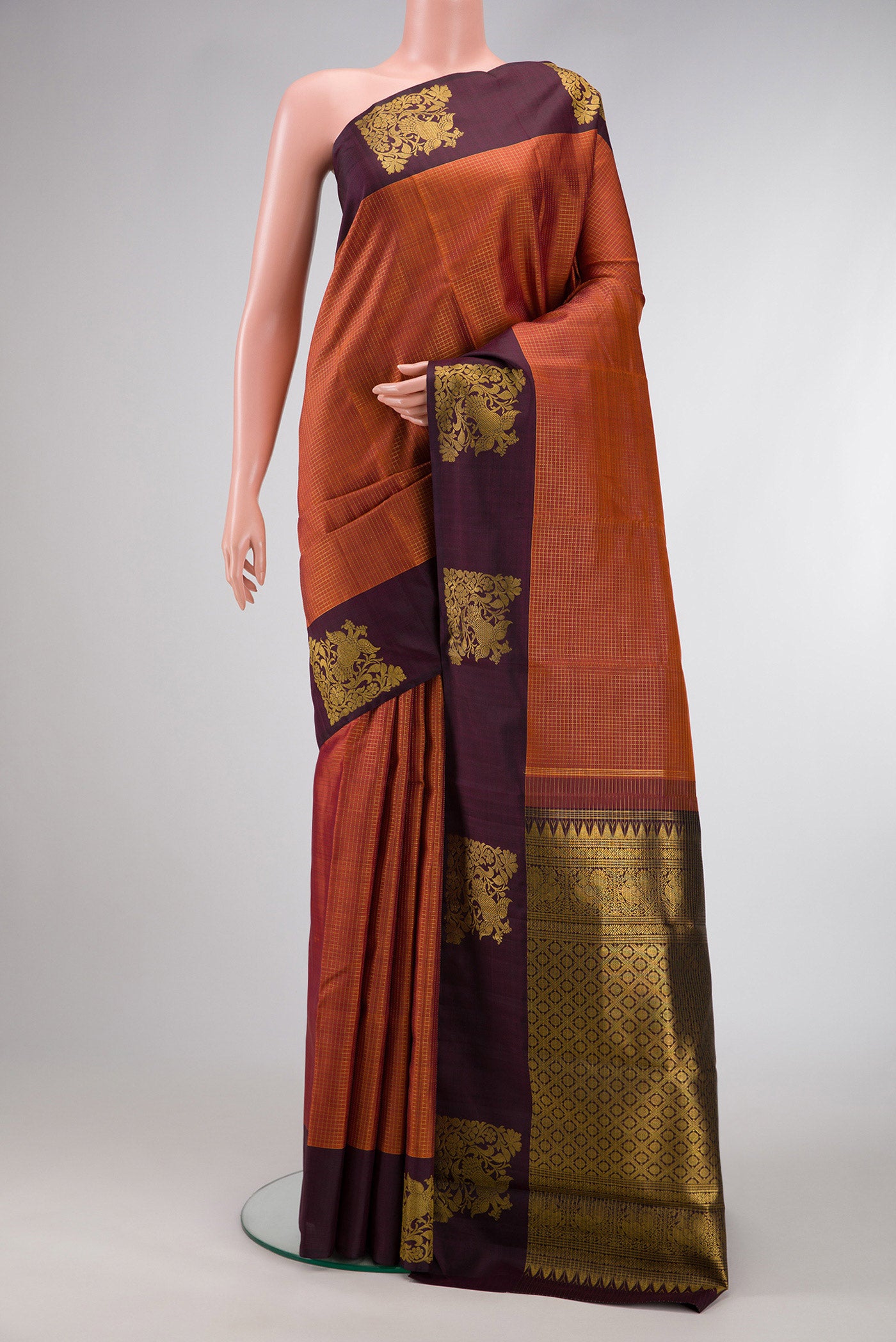 Brick Orange Dual Tone Kanjivaram Silk Saree with Checked design on the body and Fancy Border.  displayed on a mannequin