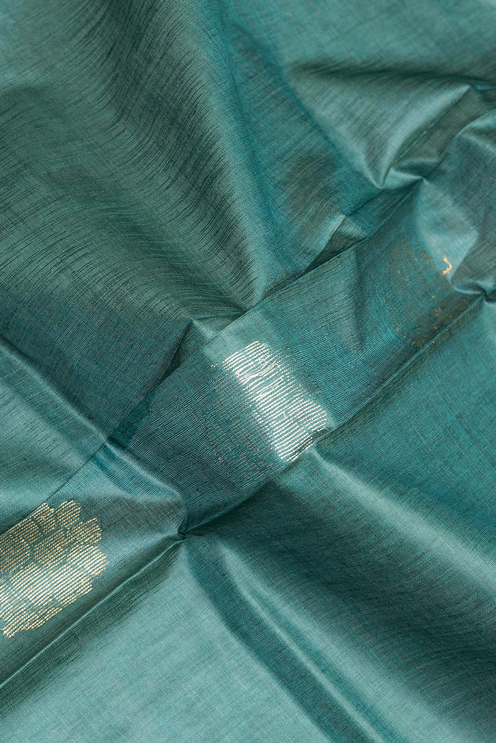 Close up of Pure Silk Green Dual Tone Tussar Saree with Zari Butta on the body and Zari Border.  displaying folds