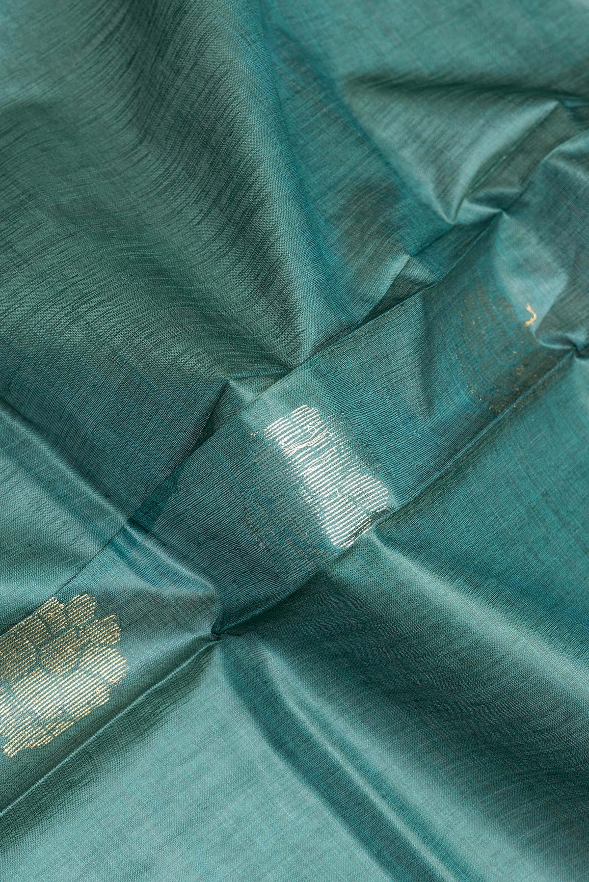 Close up of Pure Silk Green Dual Tone Tussar Saree with Zari Butta on the body and Zari Border.  displaying folds