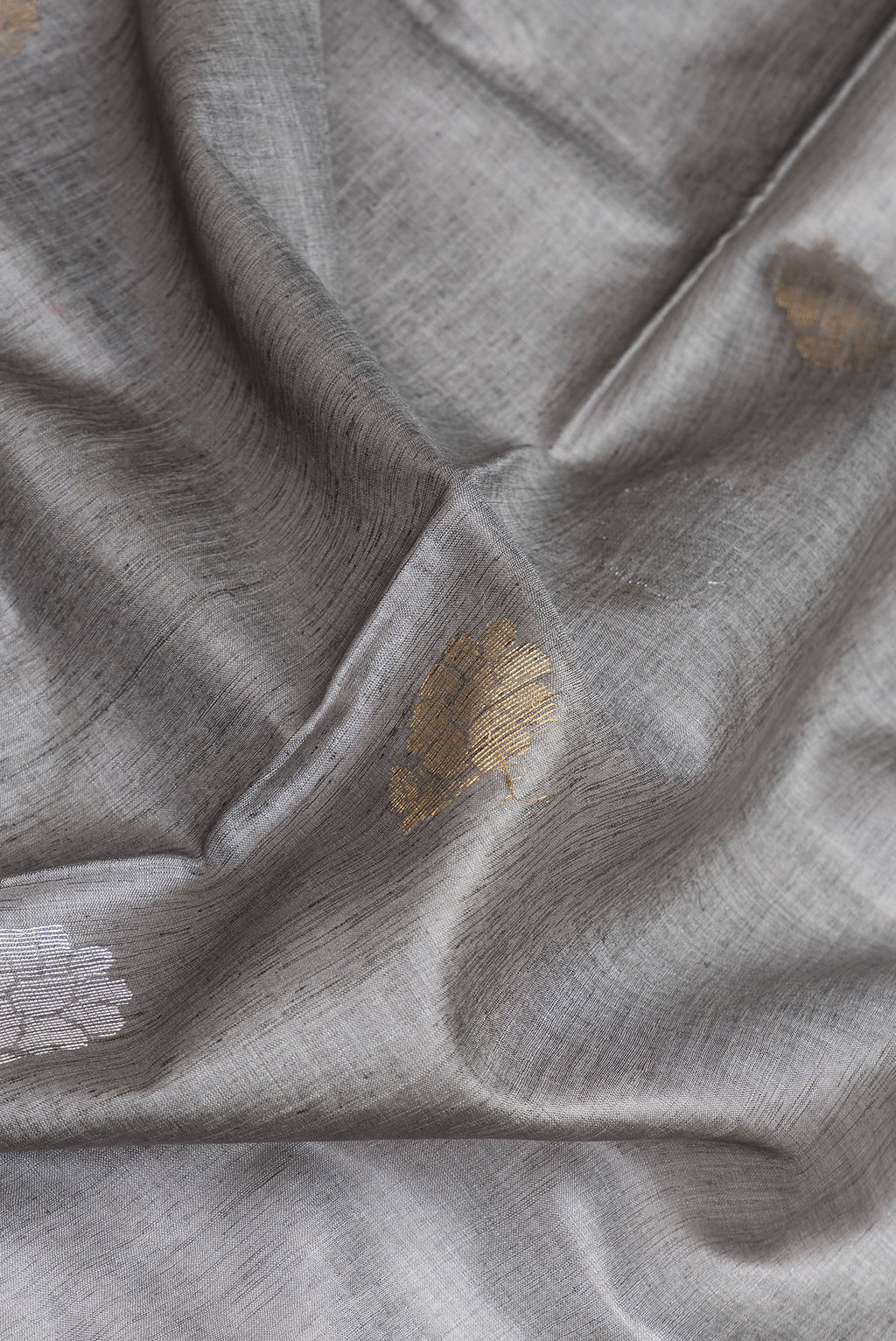 Close up of Grey Tussar Silk Saree with Zari Butta on the body and Zari Border.  displaying folds