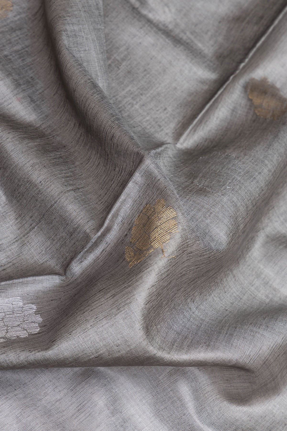 Close up of Grey Tussar Silk Saree with Zari Butta on the body and Zari Border.  displaying folds
