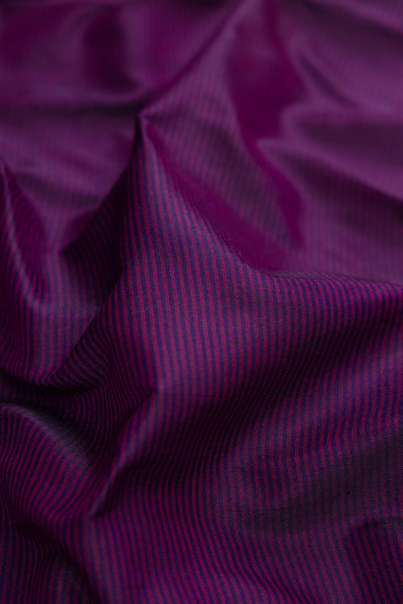 Close up of Burgundy Dual Tone Maheshwari Silk Saree with Stripes on the body and Zari Border.  displaying folds