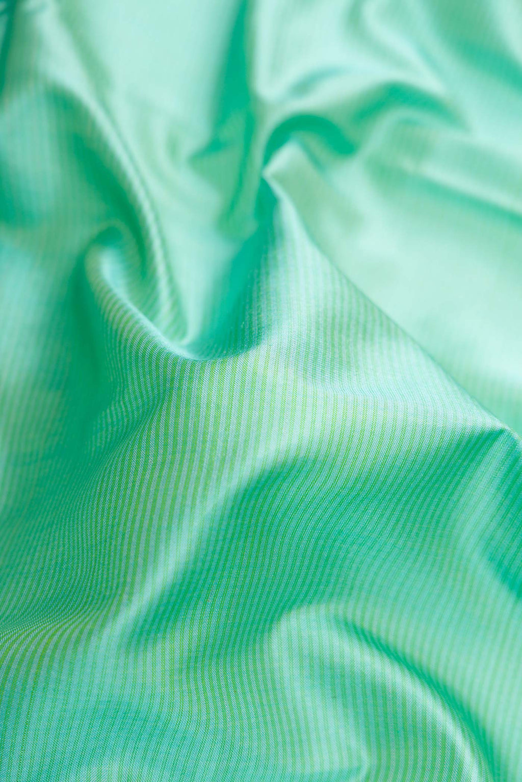 Close up of Sea Green Dual Tone Maheshwari Silk Saree with Stripes on the body and Zari Border.  displaying folds