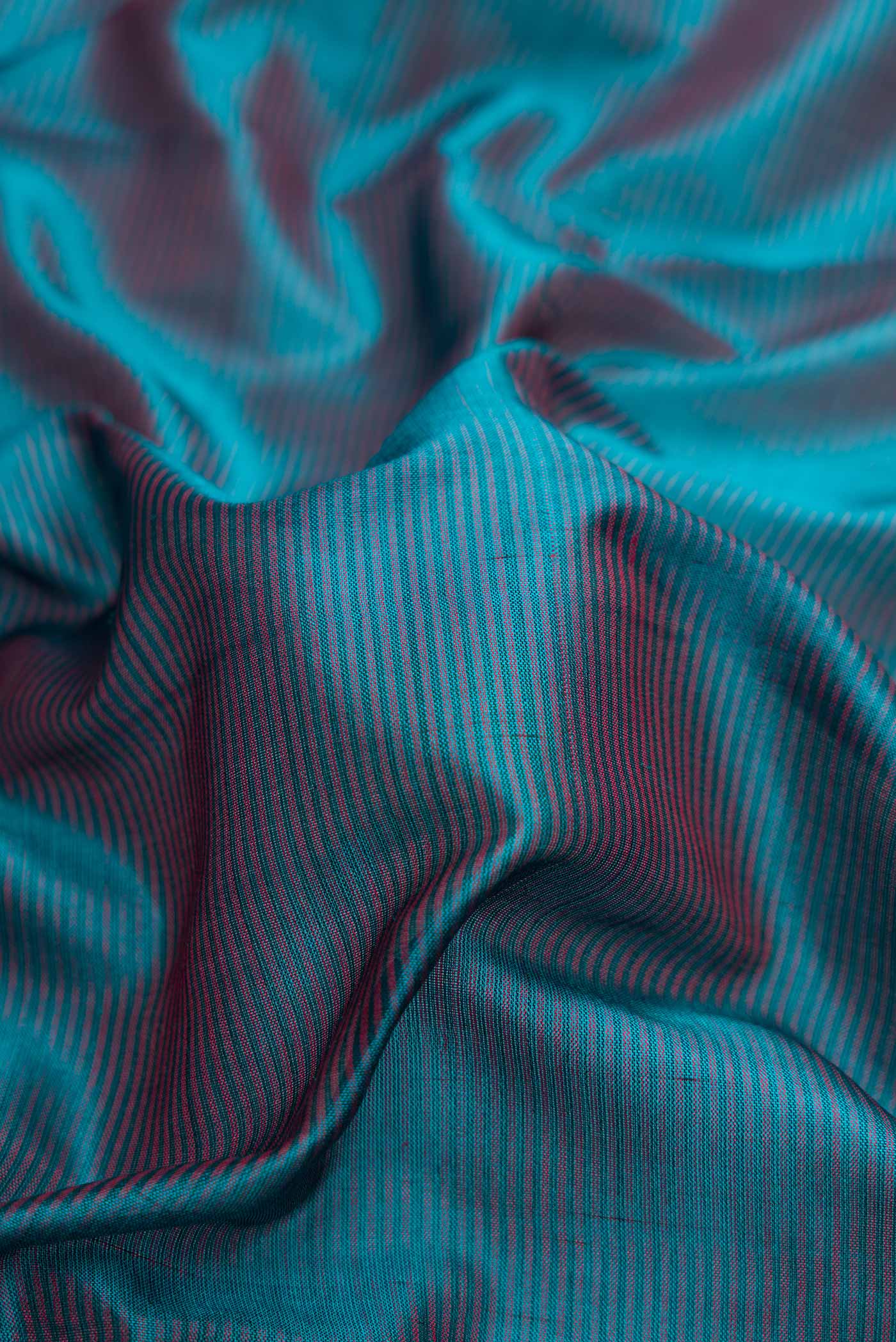 Close up of Peacock Blue Dual Tone Maheshwari Silk Saree with Stripes on the body and Zari Border.  displaying folds