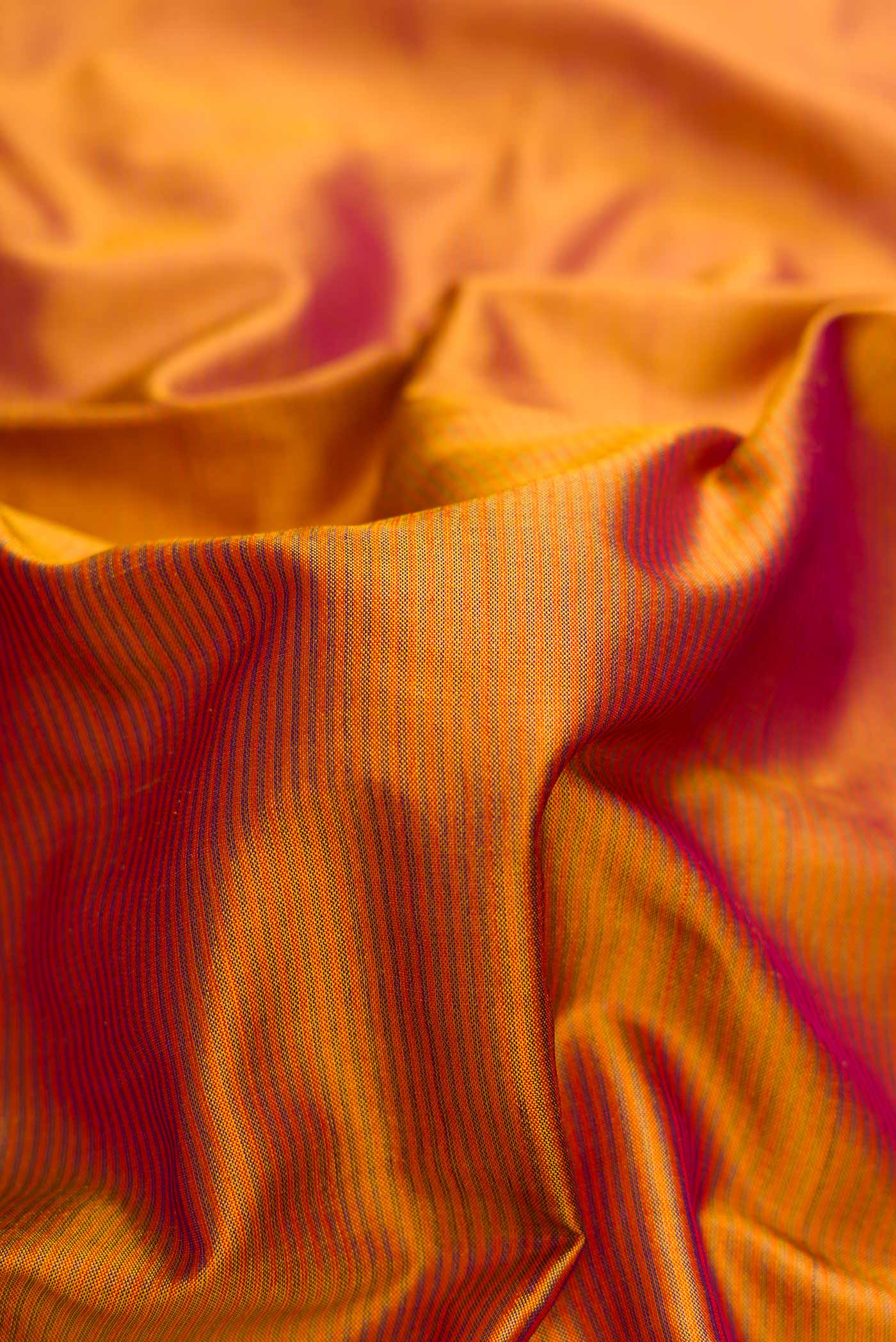 Close up of Mustard Dual Tone Maheshwari Silk Saree with Stripes on the body and Zari Border.  displaying folds
