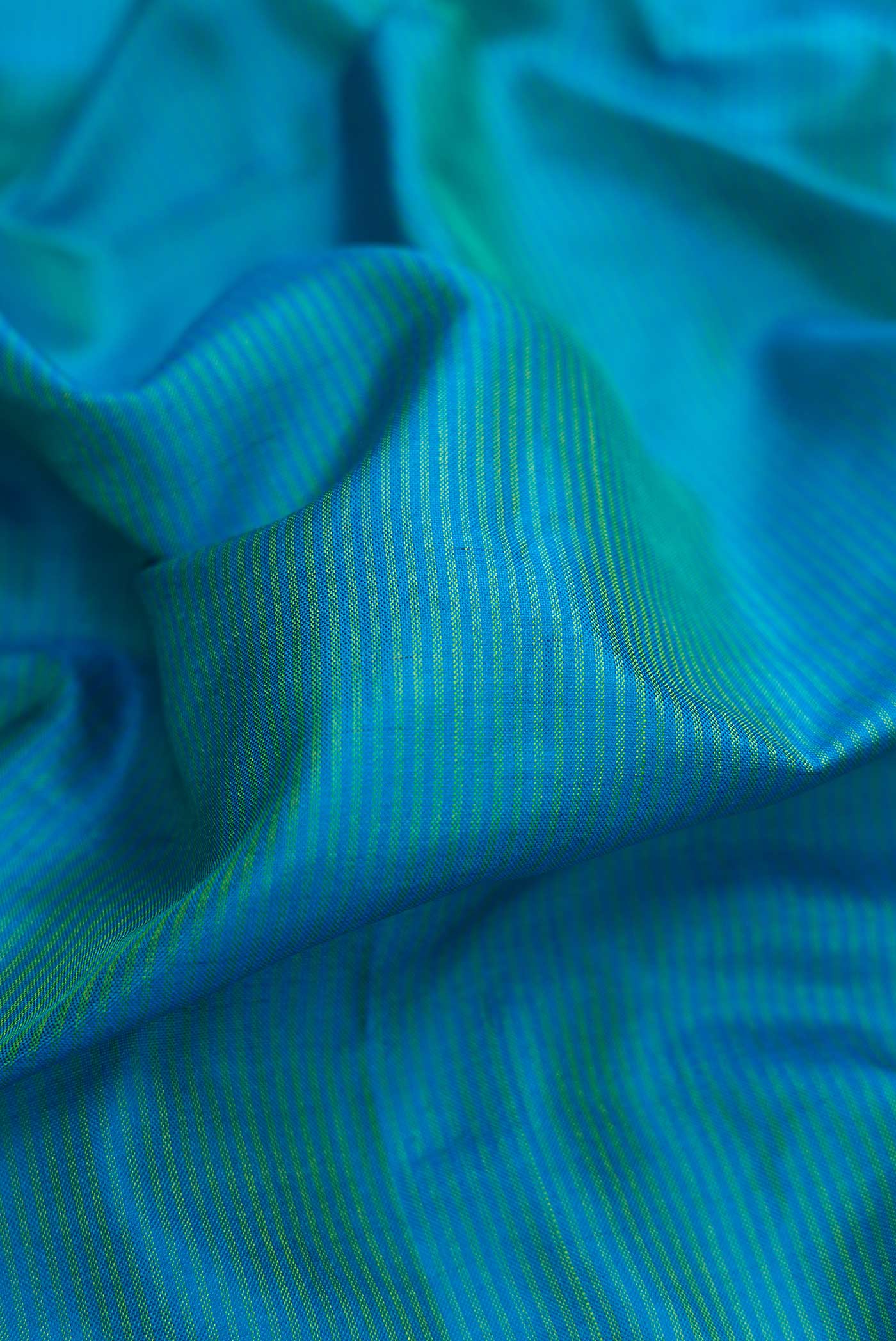 Close up of Peacock Blue Dual Tone Maheshwari Silk Saree with Stripes on the body and Zari Border.  displaying folds