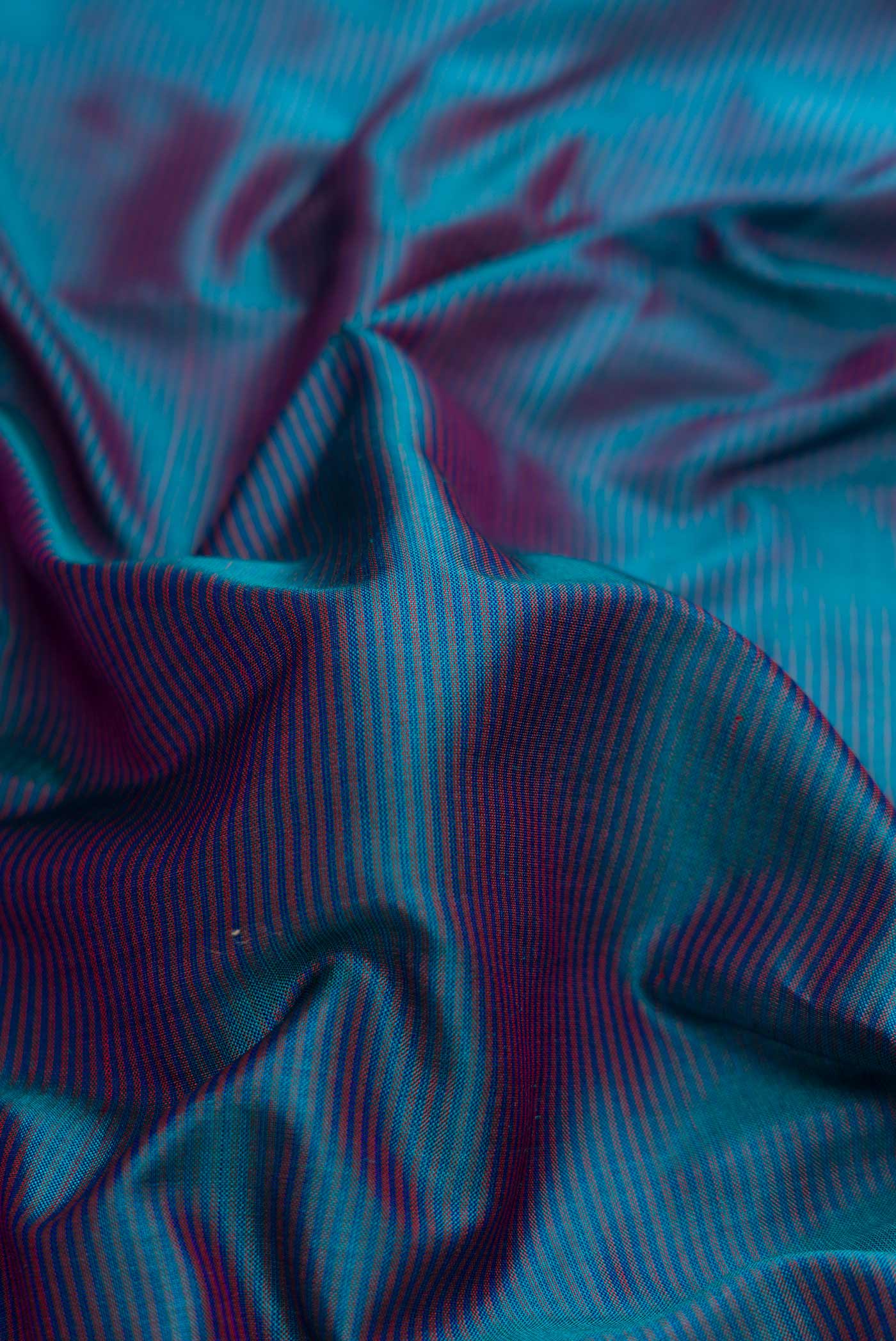 Close up of Peacock Blue Dual Tone Maheshwari Silk Saree with Stripes on the body and Zari Border.  displaying folds